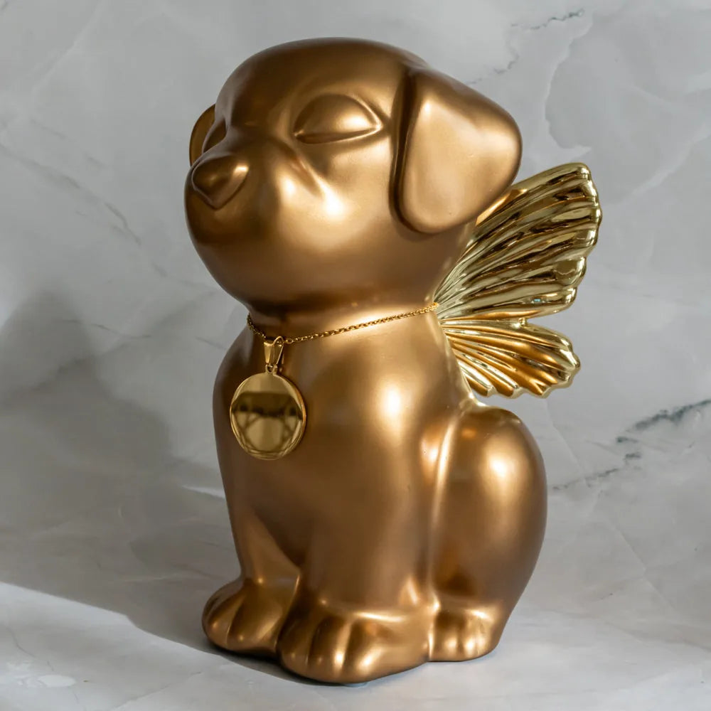 Handcrafted gold Retriever dog urn with angel wings, featuring a charm on a chain, sitting gracefully on a marble surface.