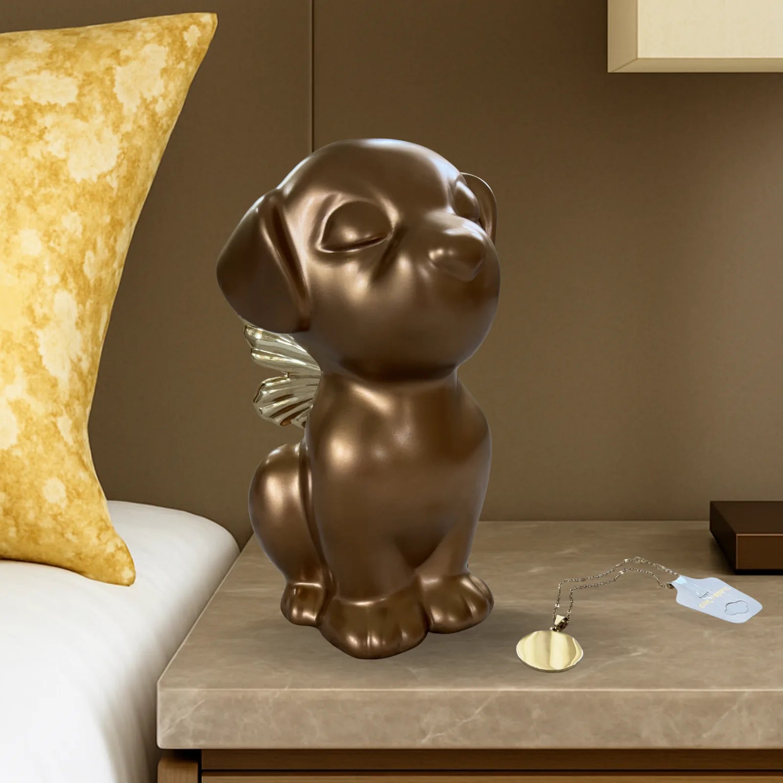Retriever Angel Dog Urn in gold with angel wings, placed on a bedside table beside a decorative pillow.