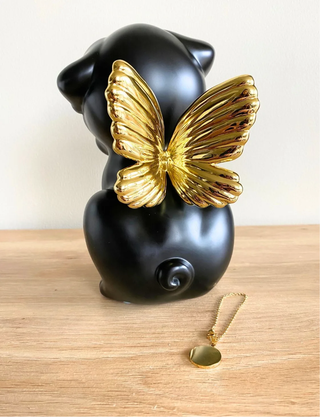 Handcrafted black dog urn with gold wings, featuring a smooth finish and a charming curled tail.