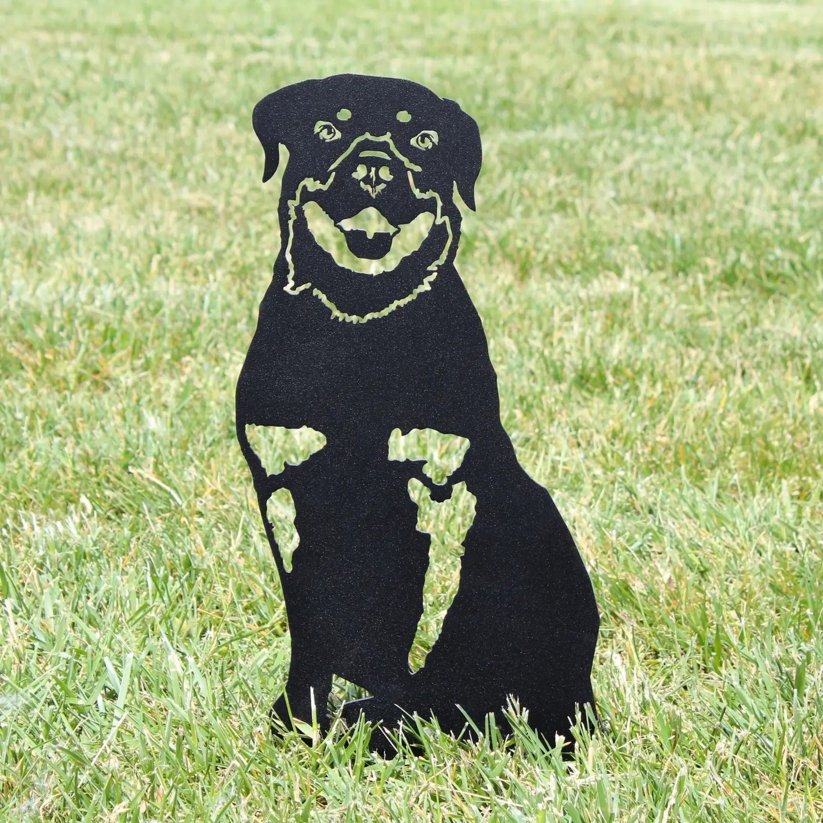 Black metal silhouette of a Rottweiler standing on grass, showcasing detailed facial features and posture.