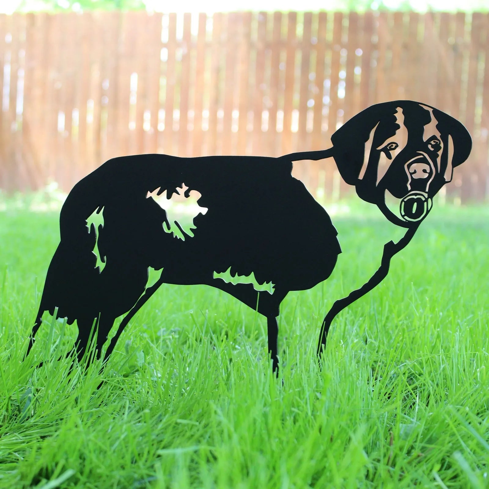 Black metal silhouette of a Saint Bernard standing on green grass, showcasing intricate detailing and design.