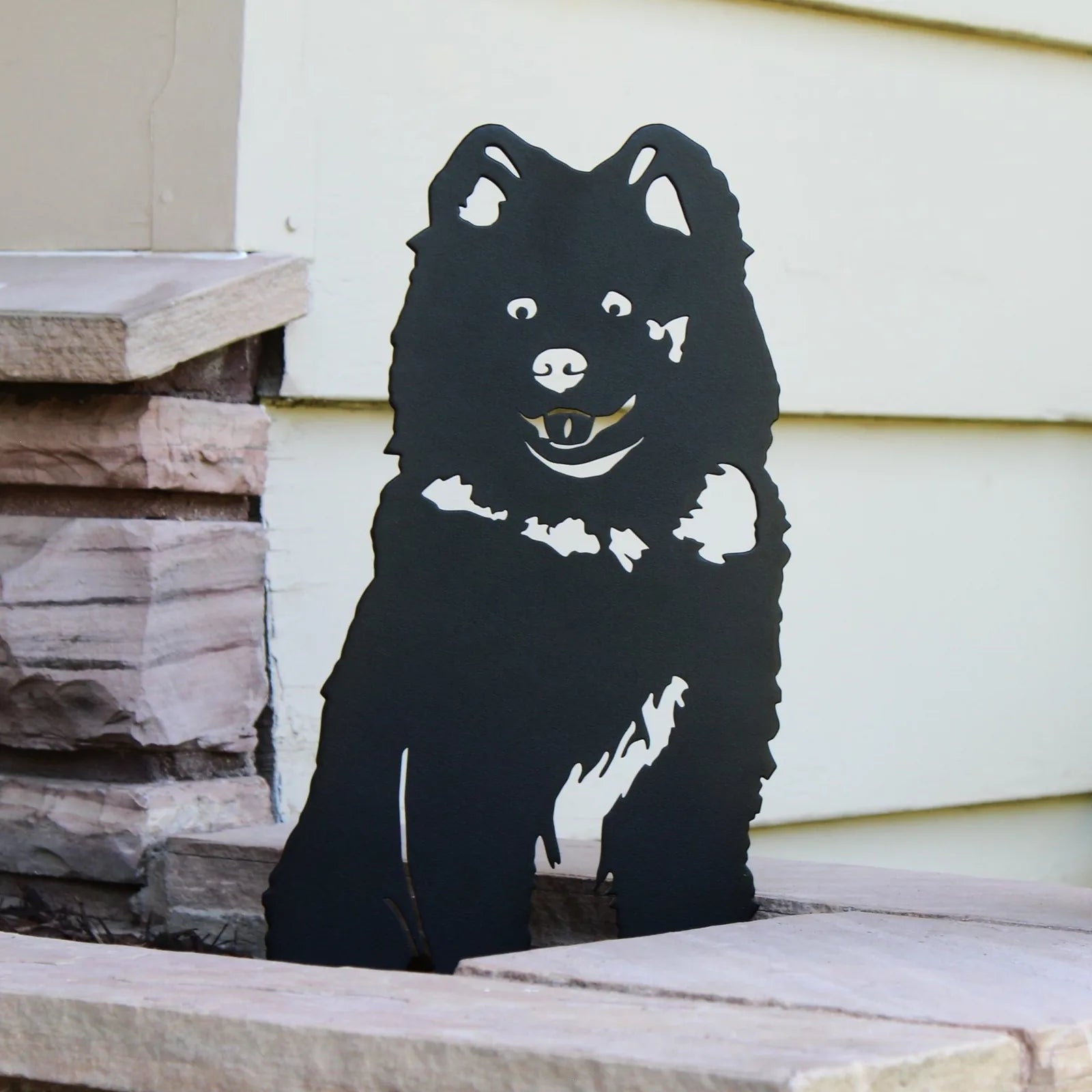 Black Samoyed silhouette decor with detailed features, displayed against a stone backdrop, ideal for outdoor spaces.