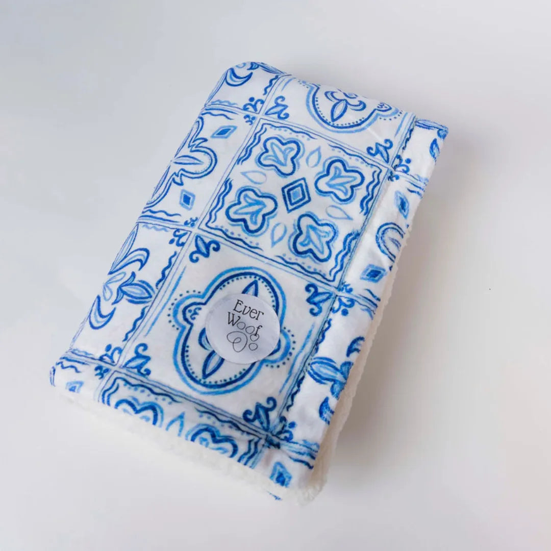 Cozy double-sided dog blanket in blue pattern and cream sherpa, perfect for snuggling and comfort during travel.