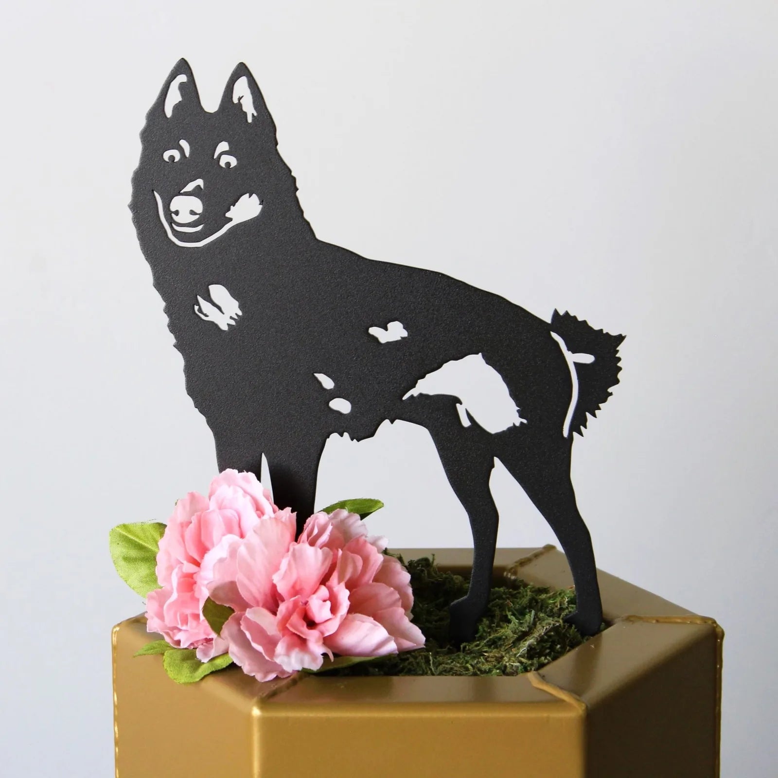 Black metal Schipperke silhouette art with pink flowers, adding rustic charm to outdoor decor or gardens.