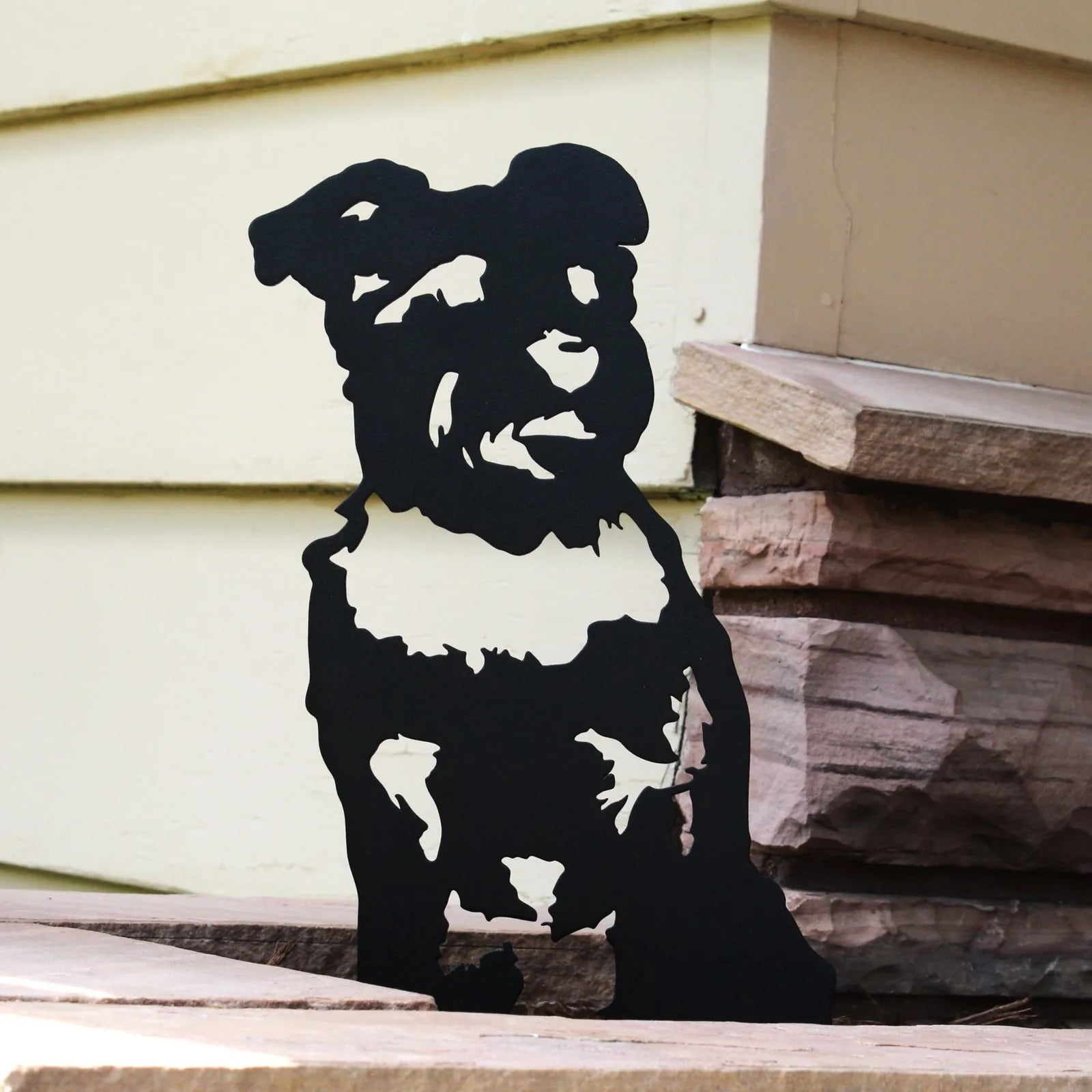 Black metal silhouette of a Schnauzer sitting against a light wall, showcasing detailed features and sturdy design.
