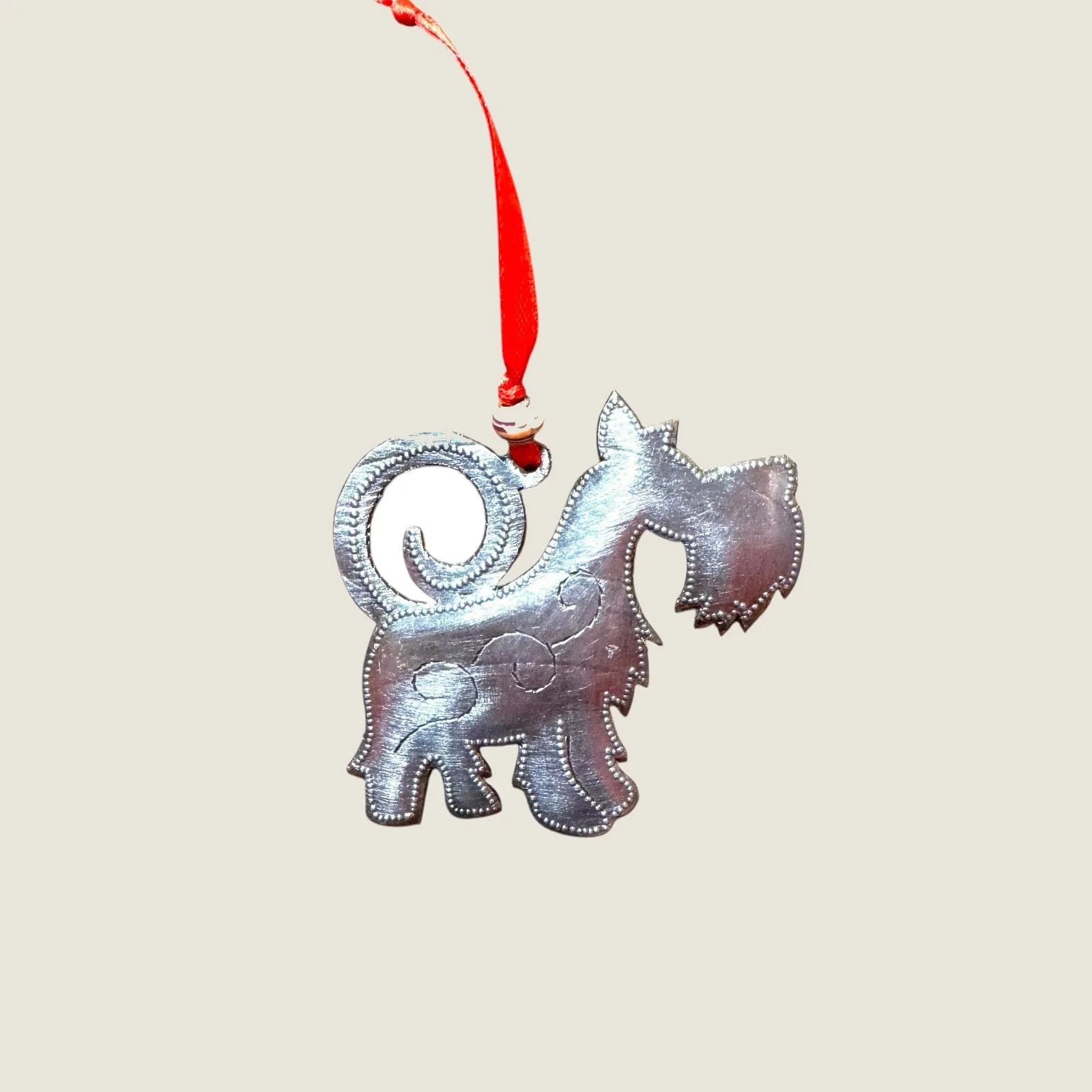 Handmade silver Scottie dog ornament with a red ribbon, perfect for dog lovers and unique holiday decor.