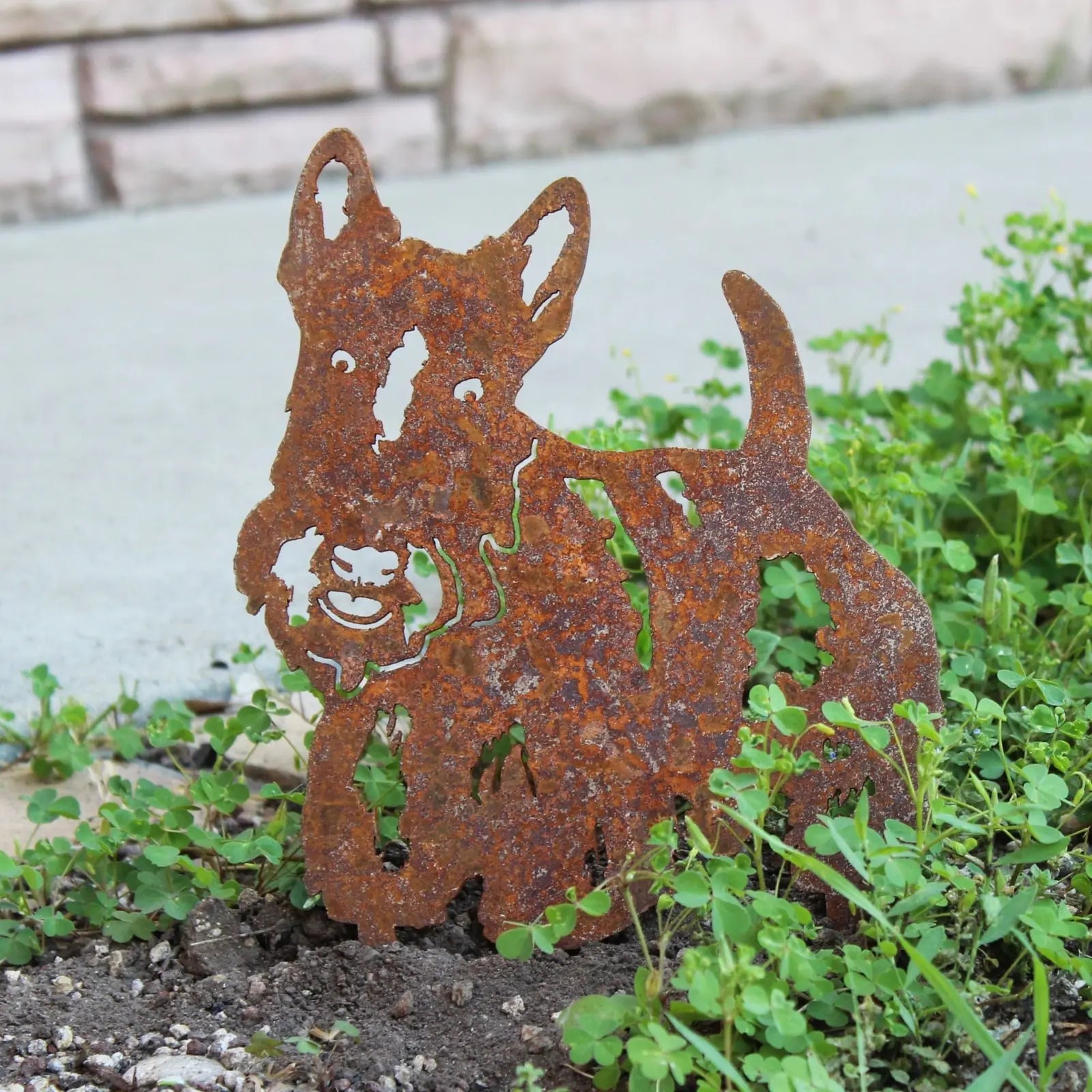 Rusty Corten steel Scottish Terrier silhouette in garden, featuring intricate cutouts and a playful expression.