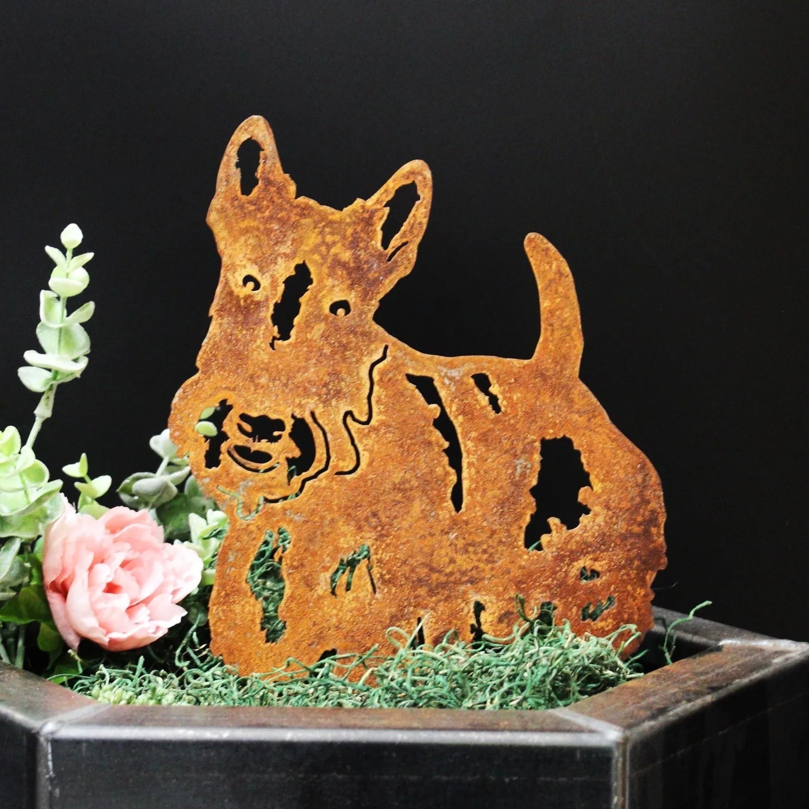 Rusty Corten steel Scottish Terrier silhouette nestled in greenery, enhancing garden decor with rustic charm.