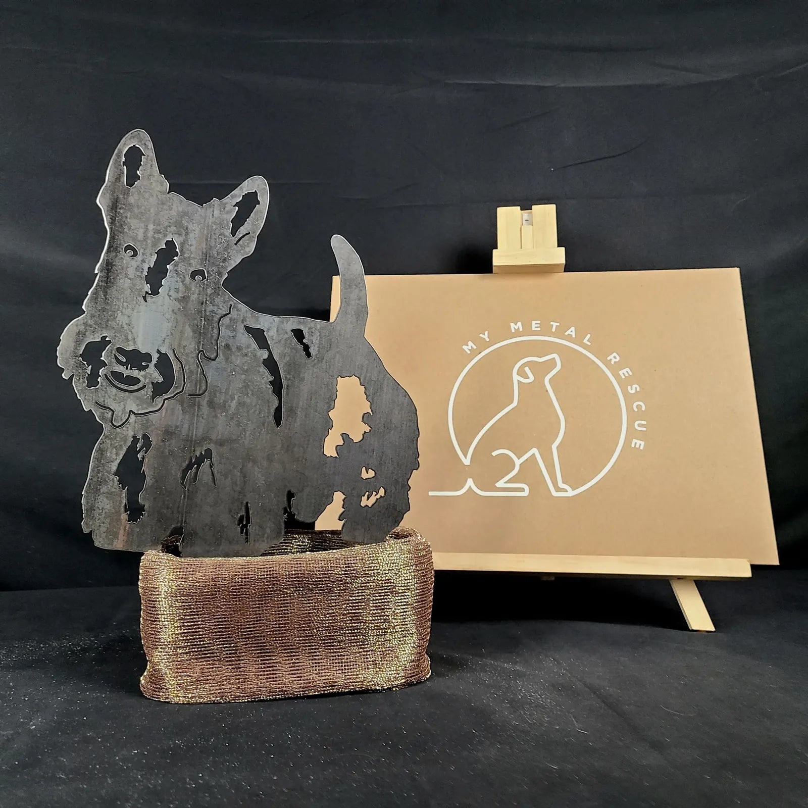 Scottish Terrier metal silhouette in Corten steel with a rustic finish, standing on a textured base, against a neutral bac...