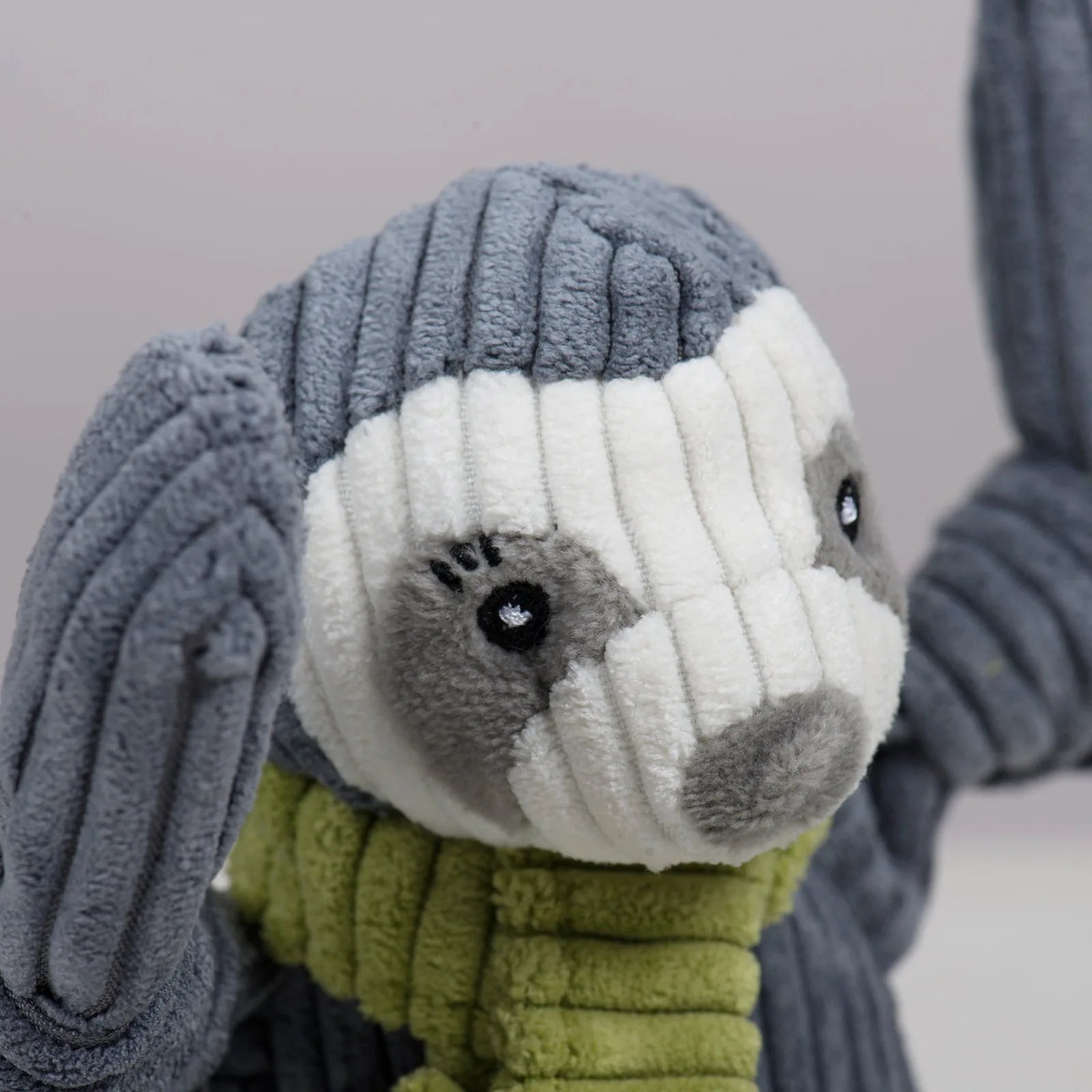Plush Seb Sloth dog toy with a soft grey body and green scarf, featuring a cute face and knotted limbs for chewing.
