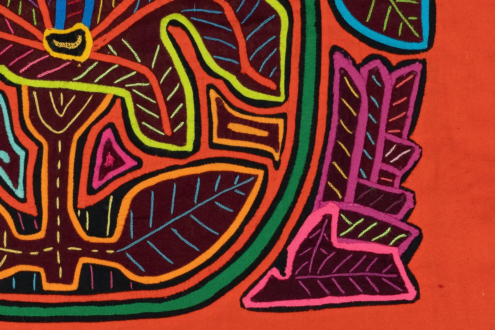 Brightly colored stitched design featuring flowers and leaves on an orange background, showcasing intricate Mola artistry.