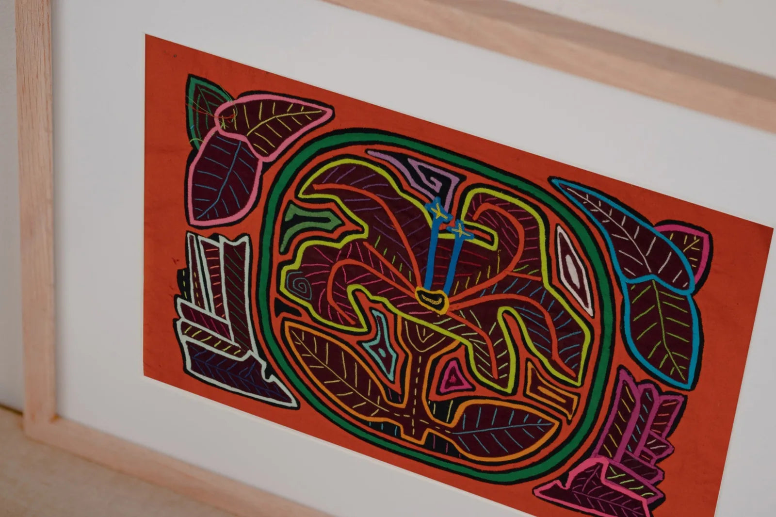 Vibrant orange tapestry featuring a shaggy puppy and floral designs, hand-stitched by Indigenous Guna artisans.