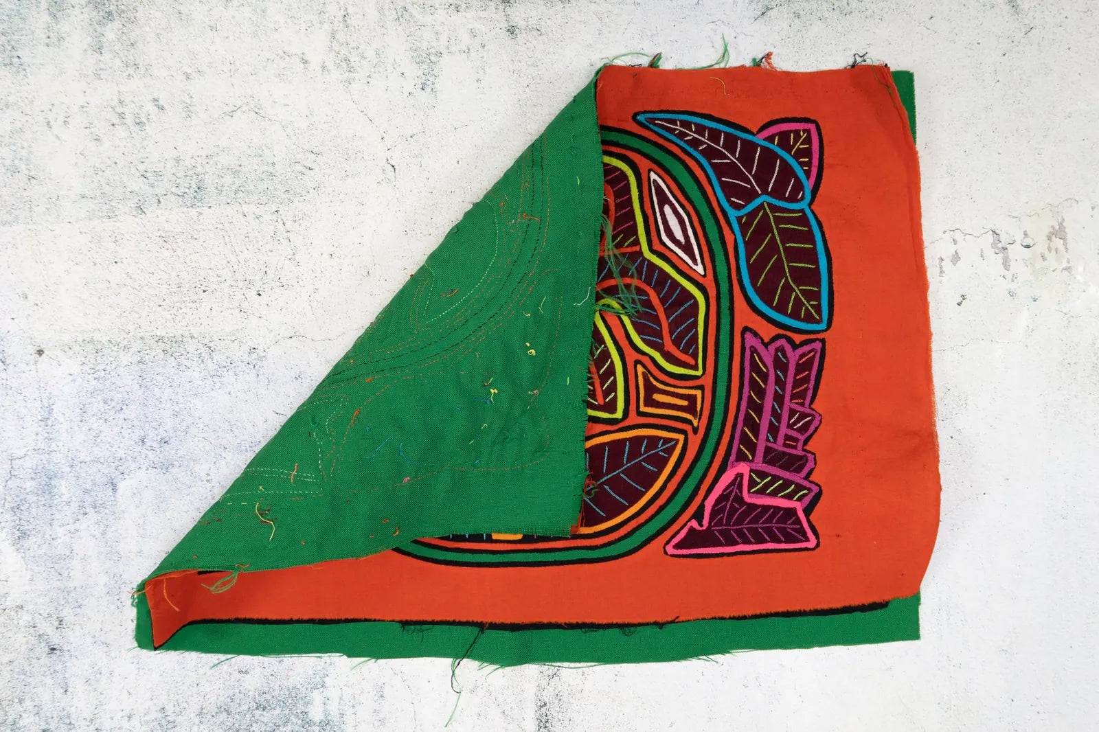 Hand-stitched tapestry featuring a shaggy puppy design in vibrant colors with green and red backgrounds.