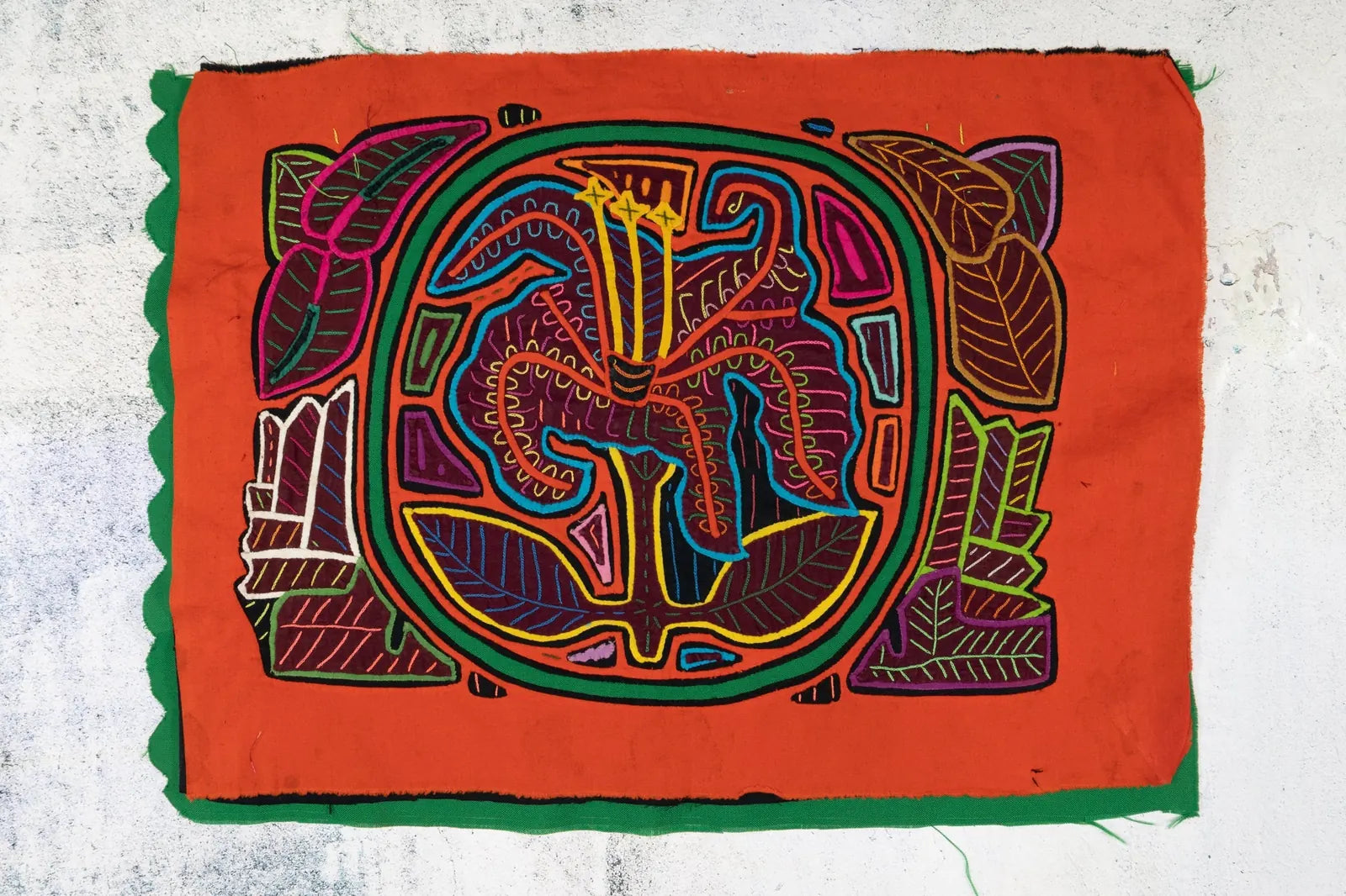 Hand-stitched vibrant orange tapestry showcasing a shaggy puppy and a flower, crafted with colorful appliqué techniques.