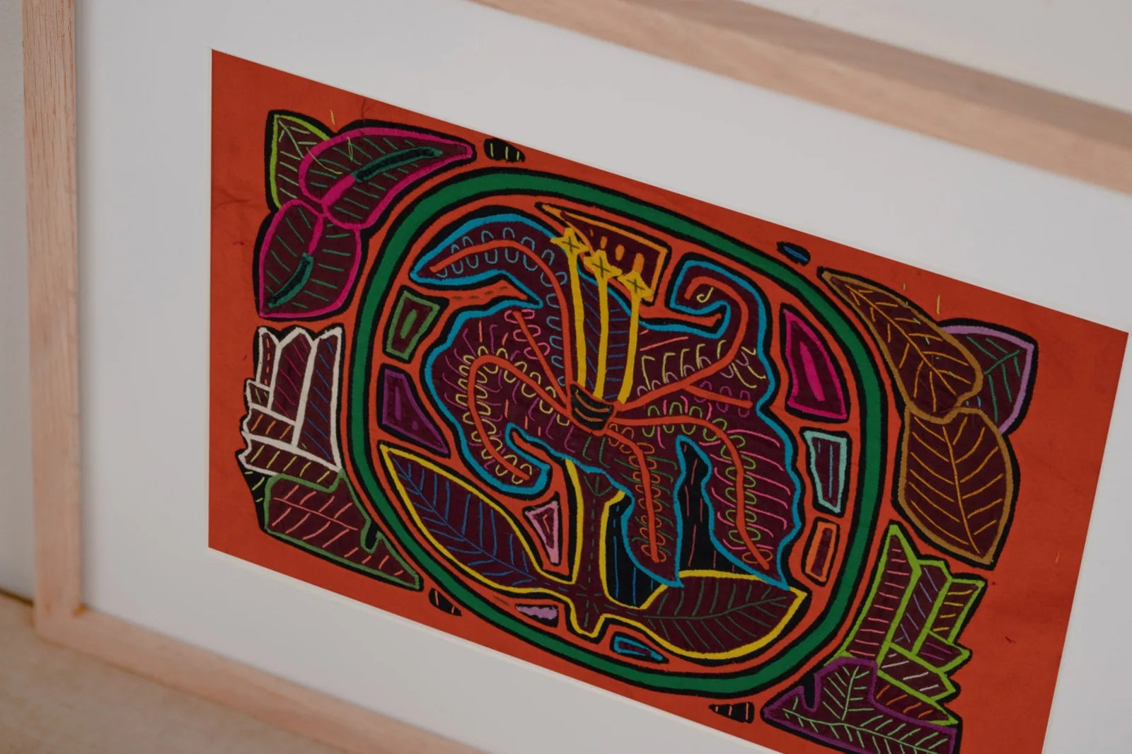 Colorful tapestry featuring a shaggy puppy and flowers, showcasing hand-stitched Mola textile art on an orange background.