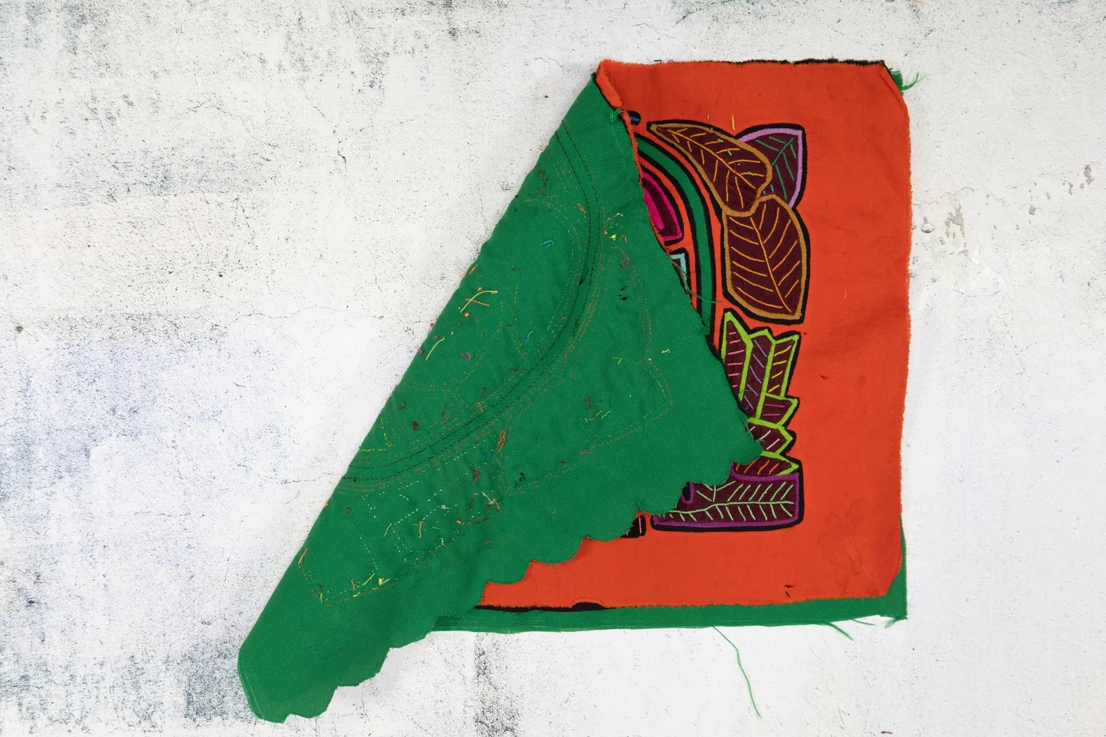 Colorful green and orange Mola tapestry featuring a shaggy puppy and floral design, handmade by indigenous Guna artisans.