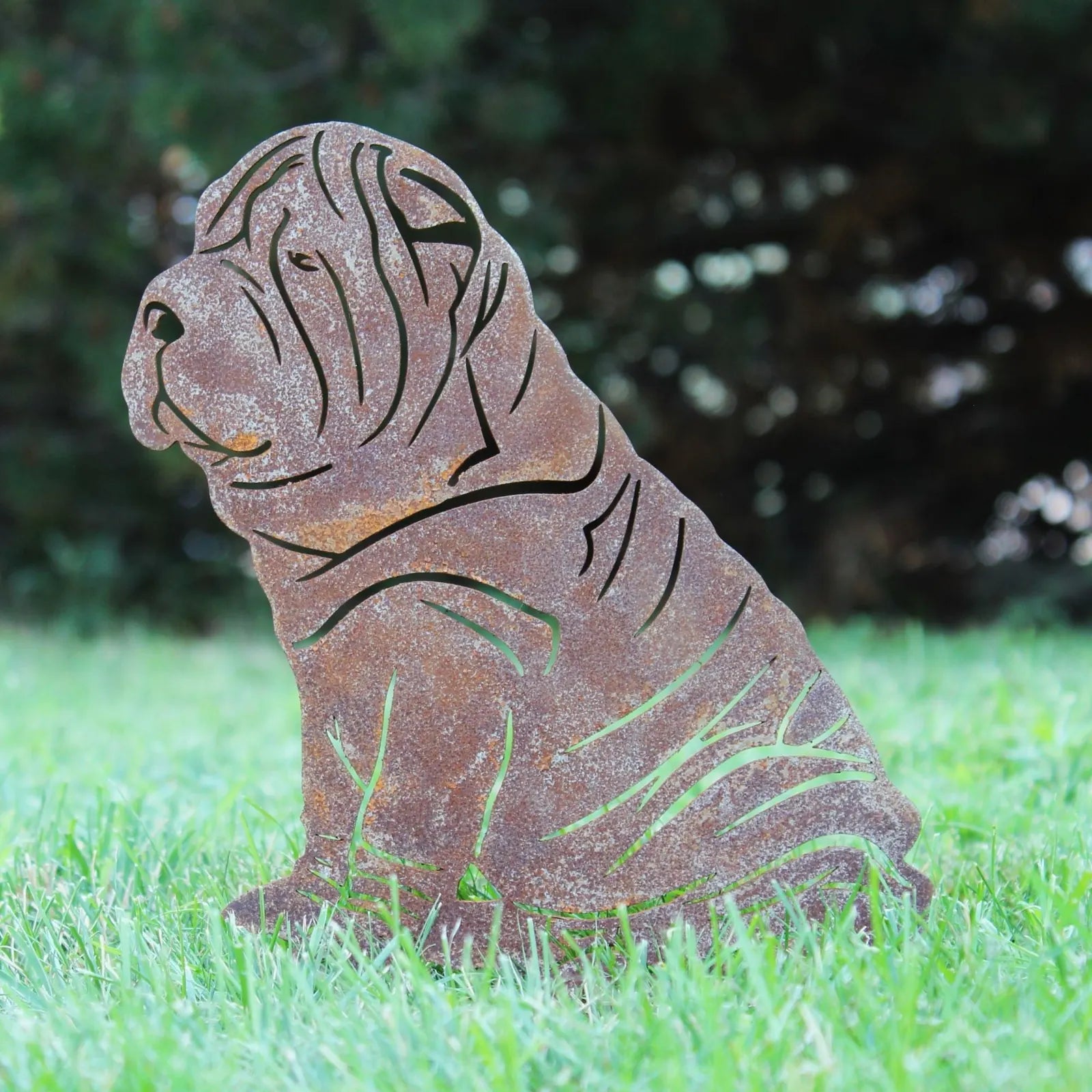 Rusty Corten steel silhouette of a seated Shar Pei, featuring intricate cut-out details, on green grass.