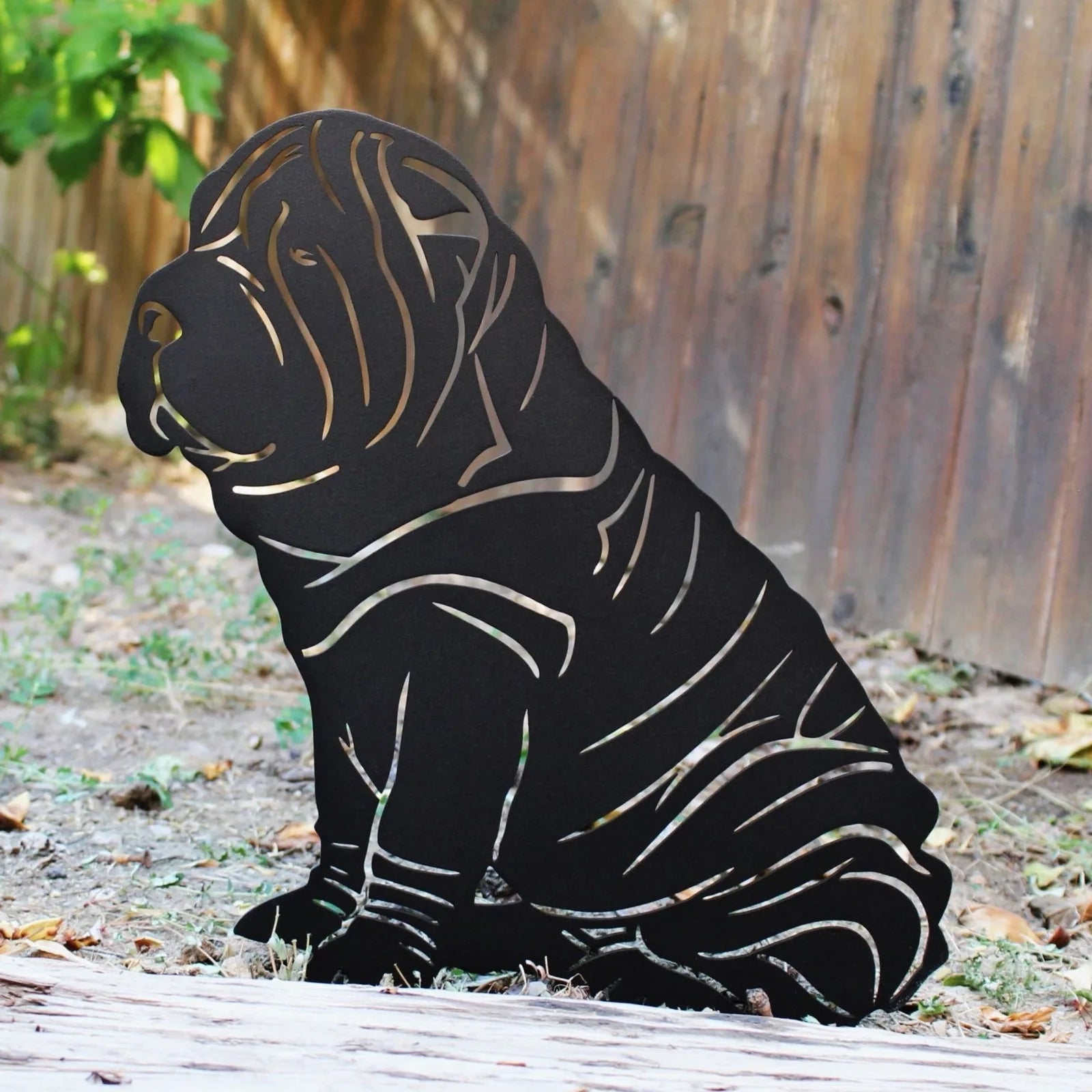 Black metal silhouette of a Shar Pei dog, showcasing detailed lines, set against a natural outdoor background.