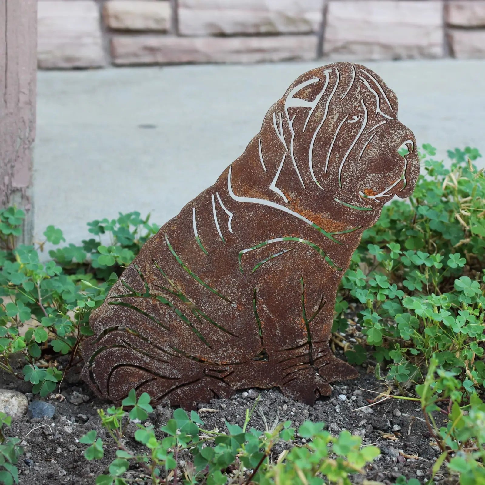 Shar Pei metal silhouette in rusted Corten steel, set among green ground cover, ideal for outdoor dog decor.