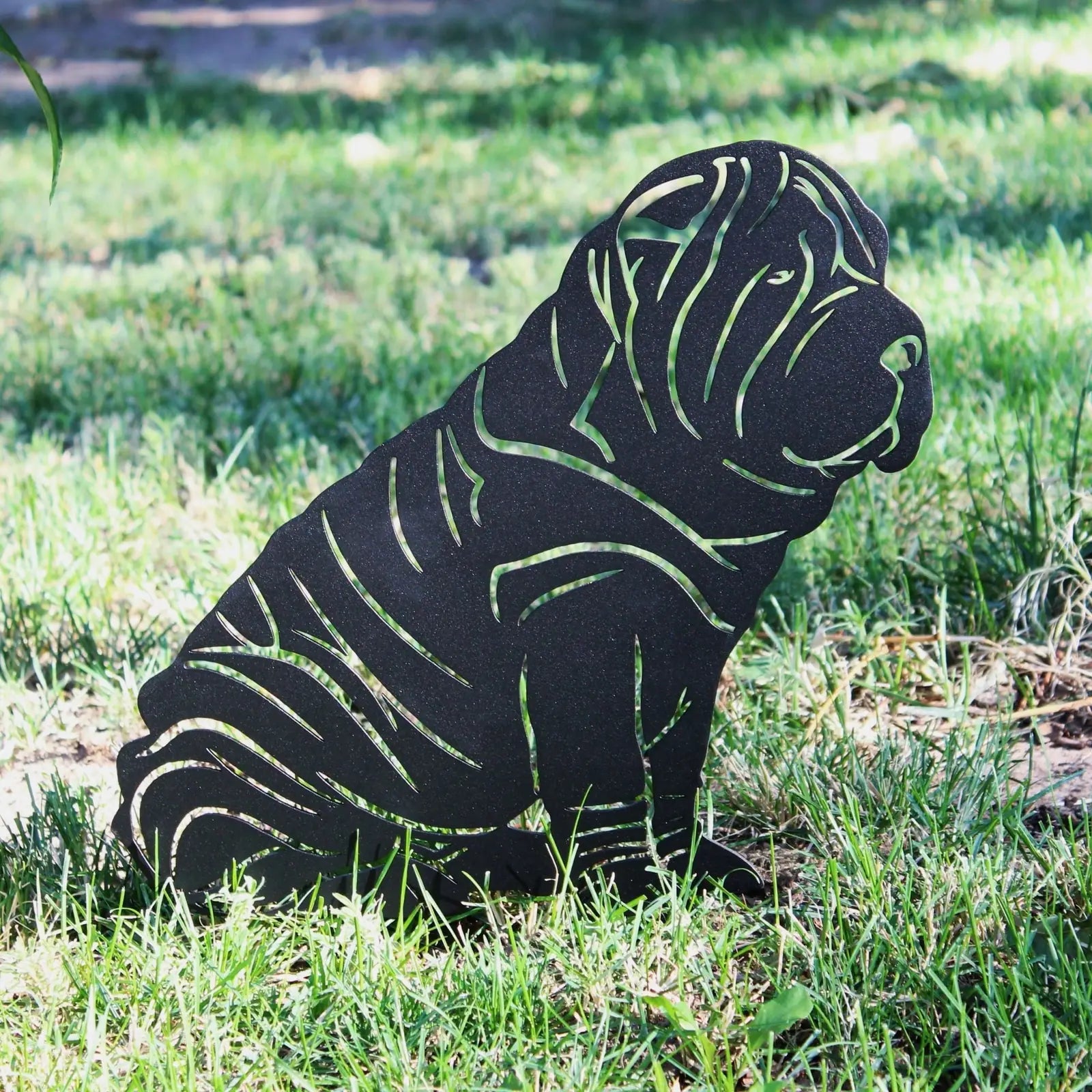 Shar Pei silhouette in matte black metal, artfully designed, sits on green grass, perfect for outdoor decor.