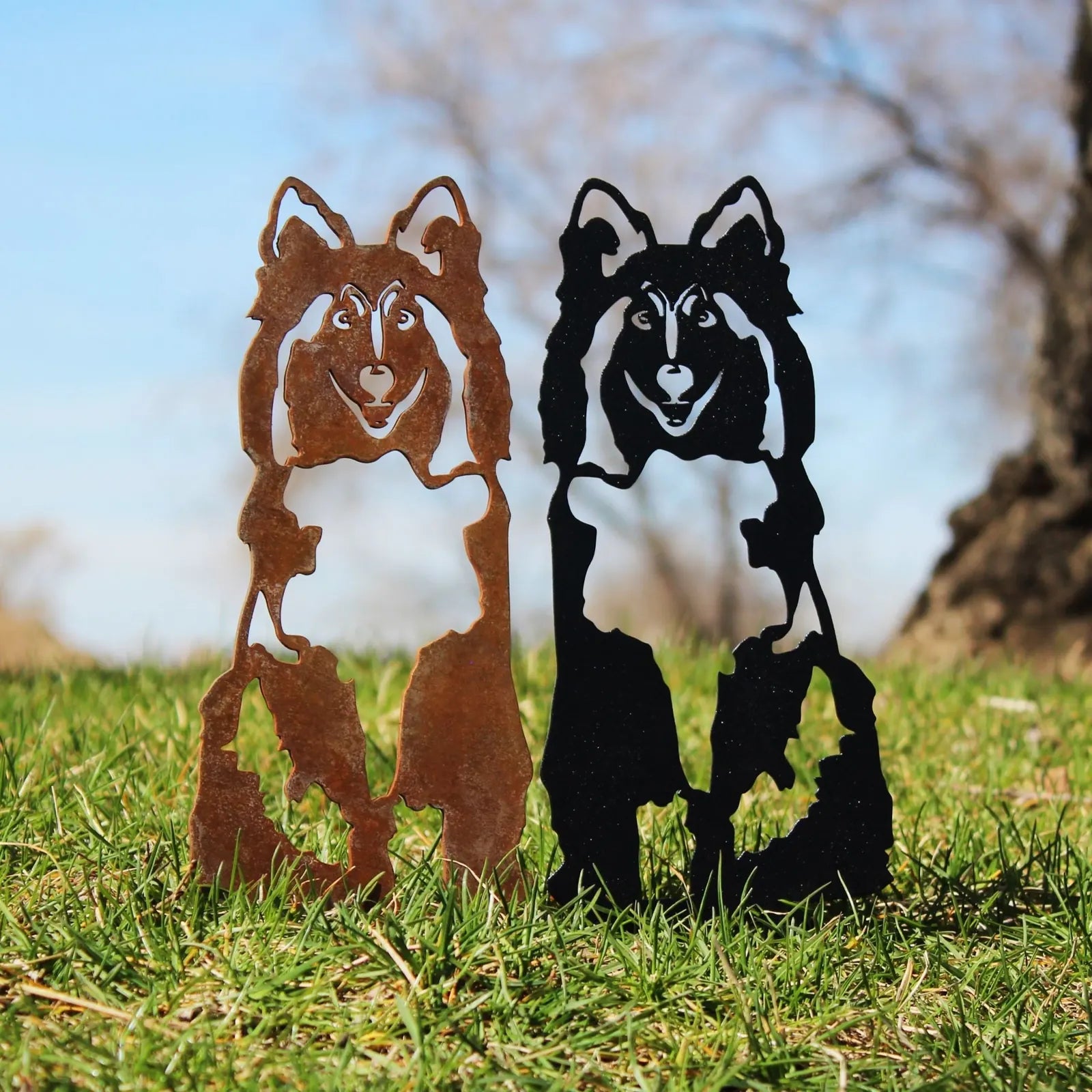 Shetland Sheepdog metal silhouettes in Corten steel and matte black, set against green grass.