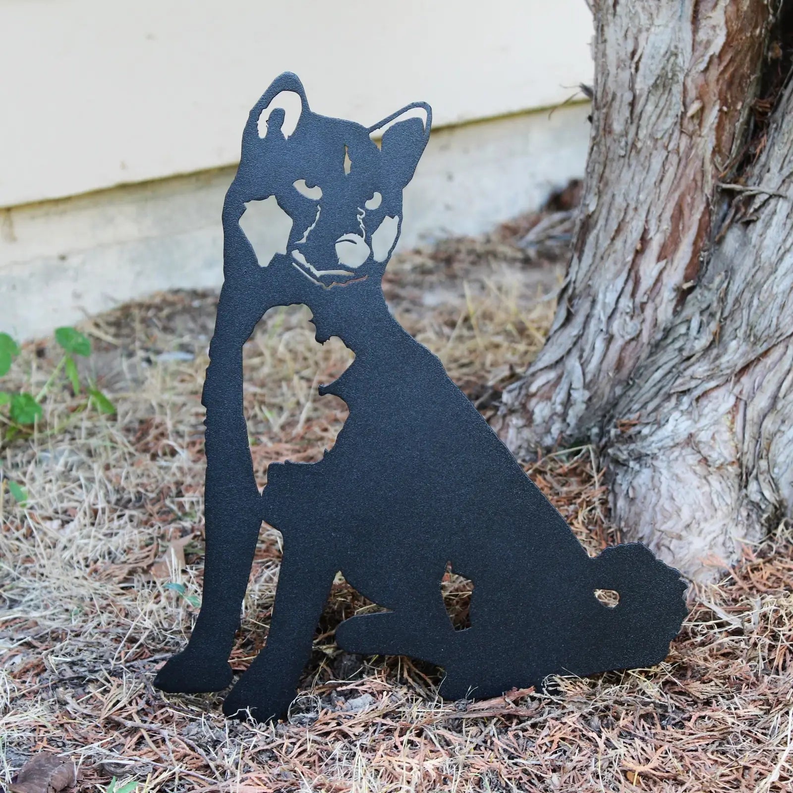 Black Shiba Inu metal silhouette sitting among pine needles, showcasing rustic outdoor decor by My Metal Rescue.