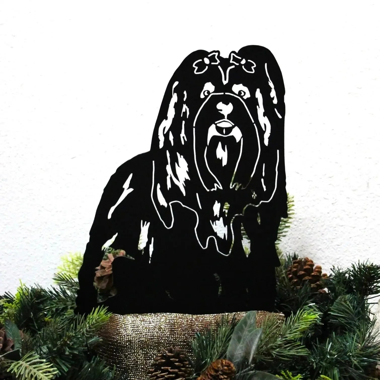 Handcrafted black metal silhouette of a Shih Tzu dog, displayed among greenery and pine cones as garden decor.