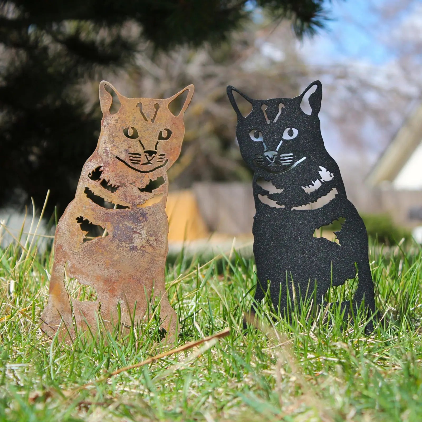Rustic Corten steel and matte black cat silhouettes in grass, perfect for outdoor decor.
