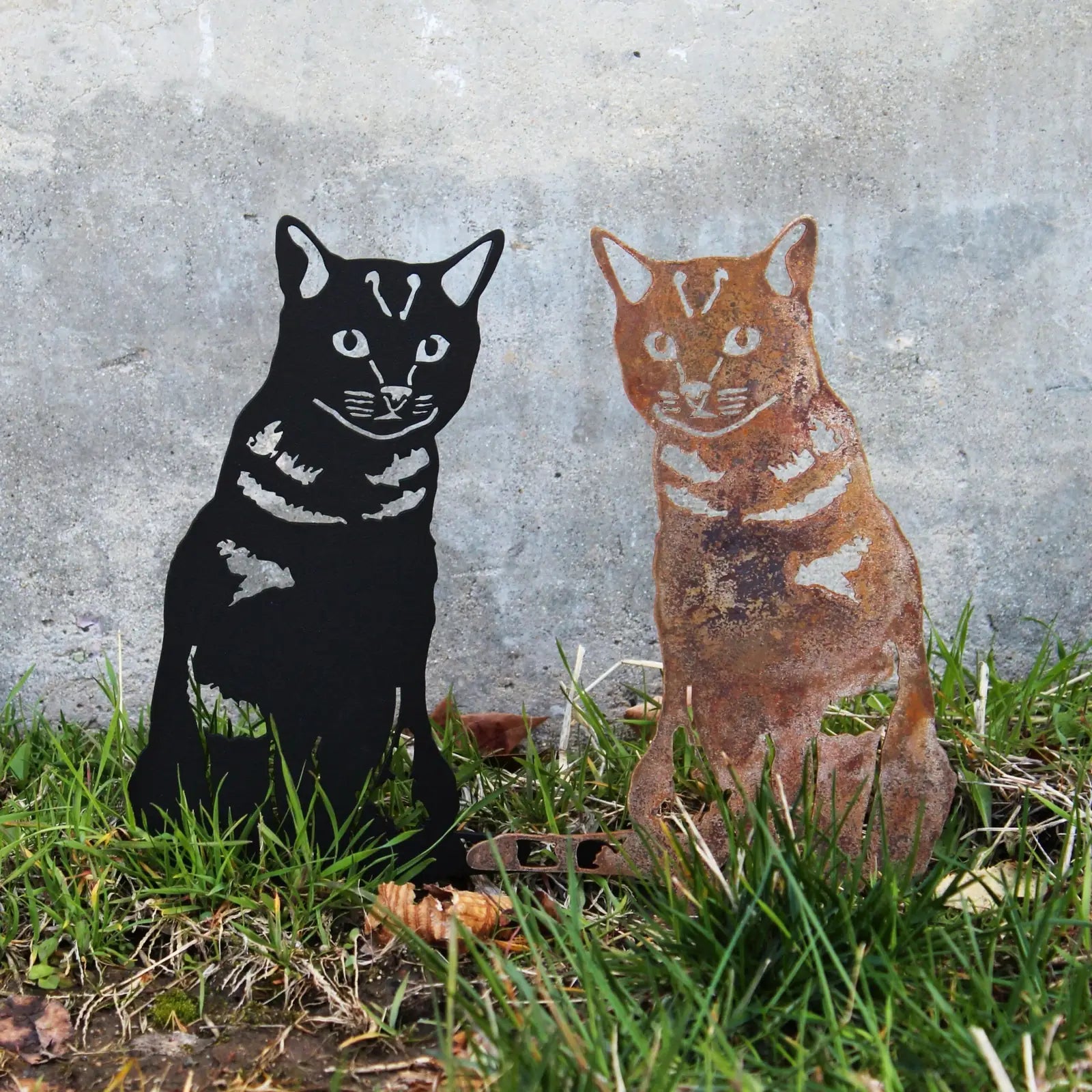 Black and rust-colored shorthair tabby metal silhouettes in grass, showcasing unique finishes and cat details.