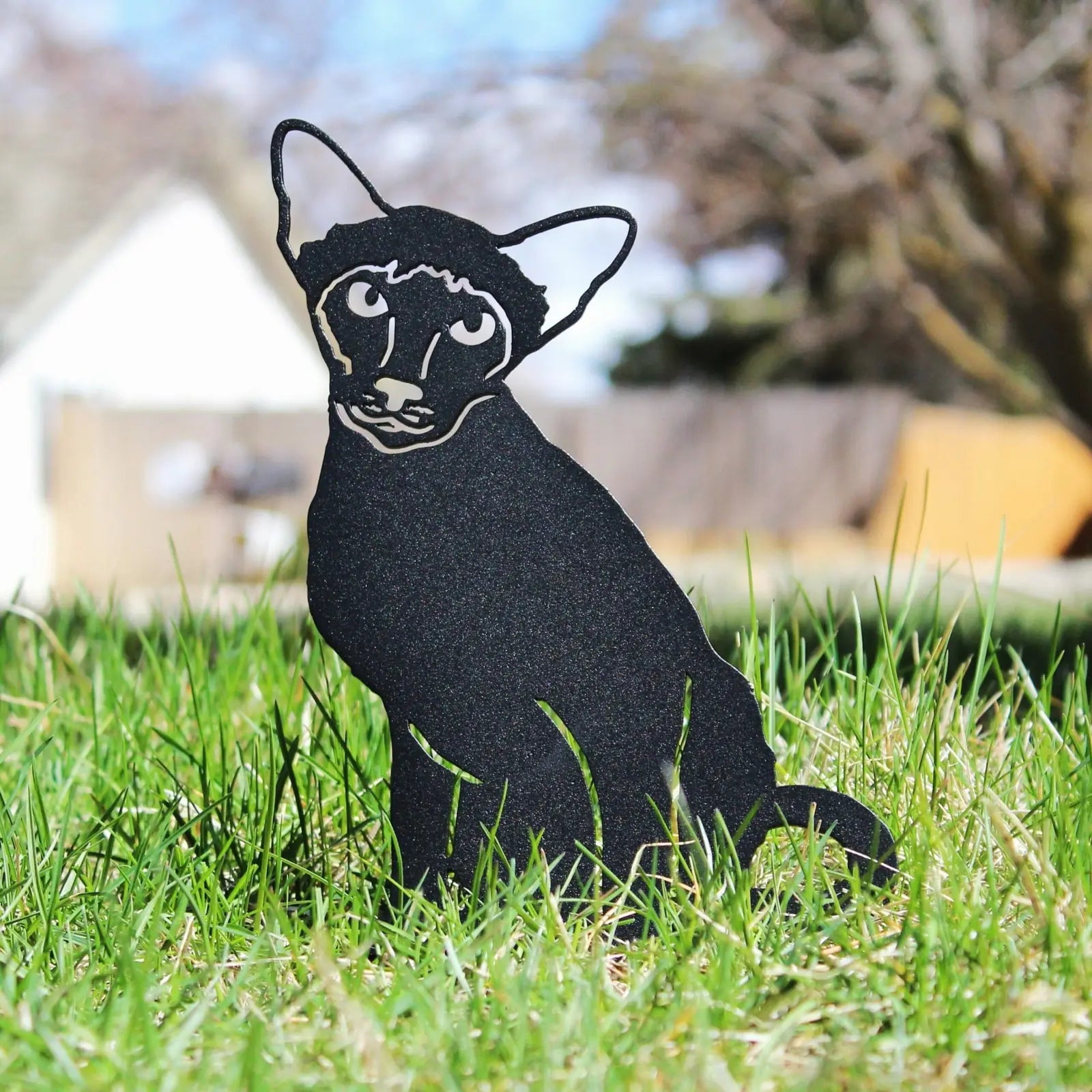 Black Siamese cat silhouette made of metal, set in lush green grass, showcasing a decorative outdoor garden accent.