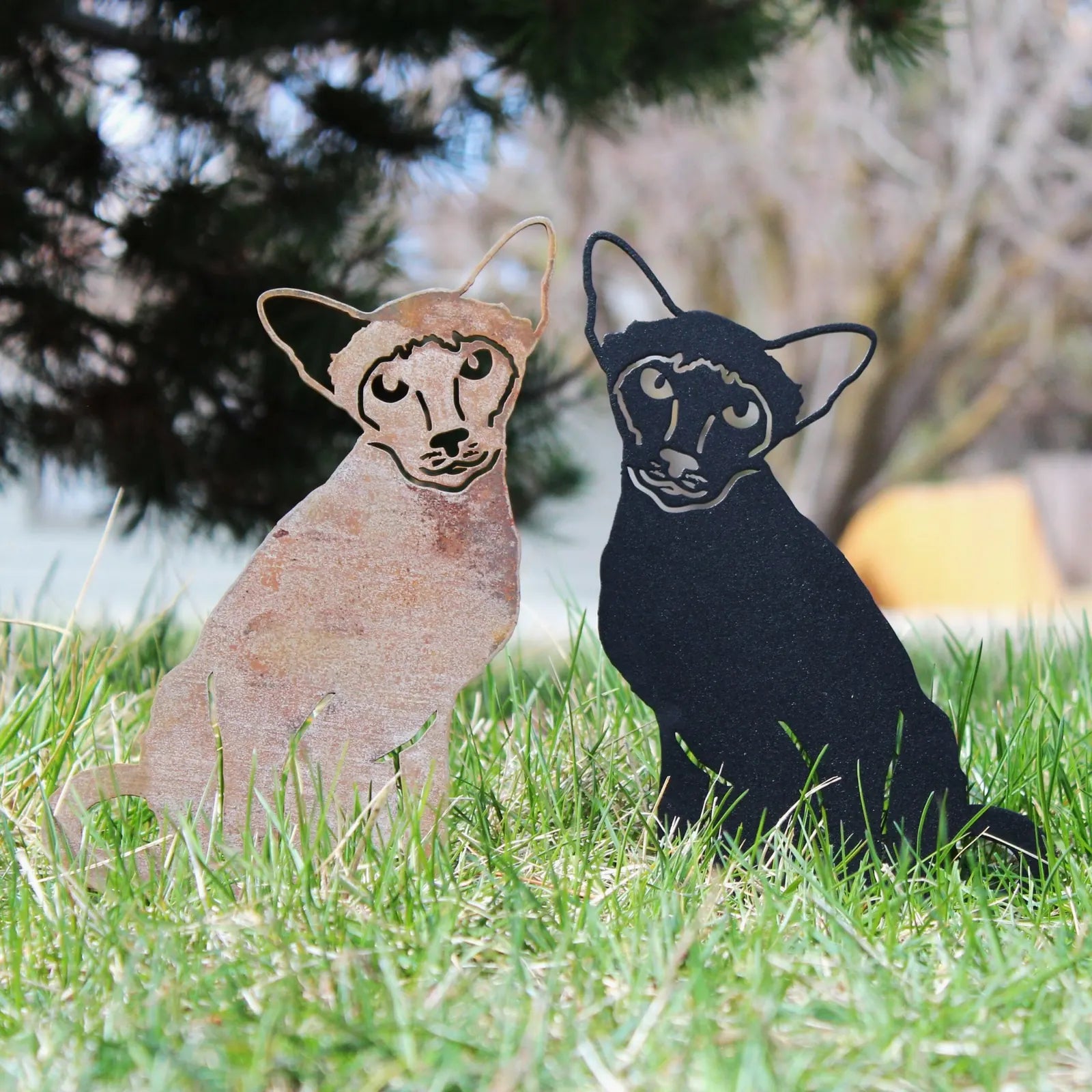 Handmade Siamese cat silhouettes in Corten steel and black metal, displayed on grass for outdoor decor.