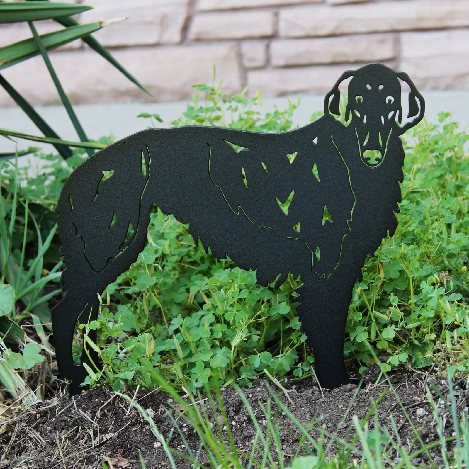 Black metal silhouette of a Silken Windhound, nestled in green plants, showcasing detailed cutouts and smooth edges.