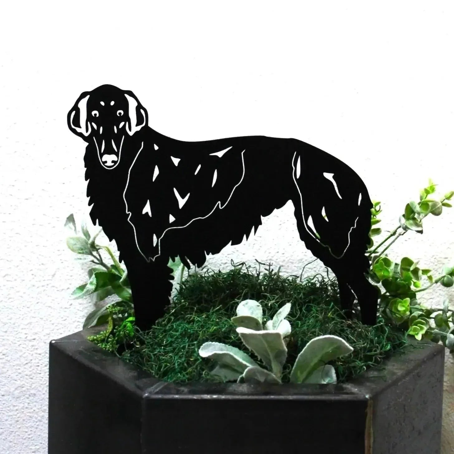 Silken Windhound metal silhouette in matte black, positioned in a planter with green foliage.