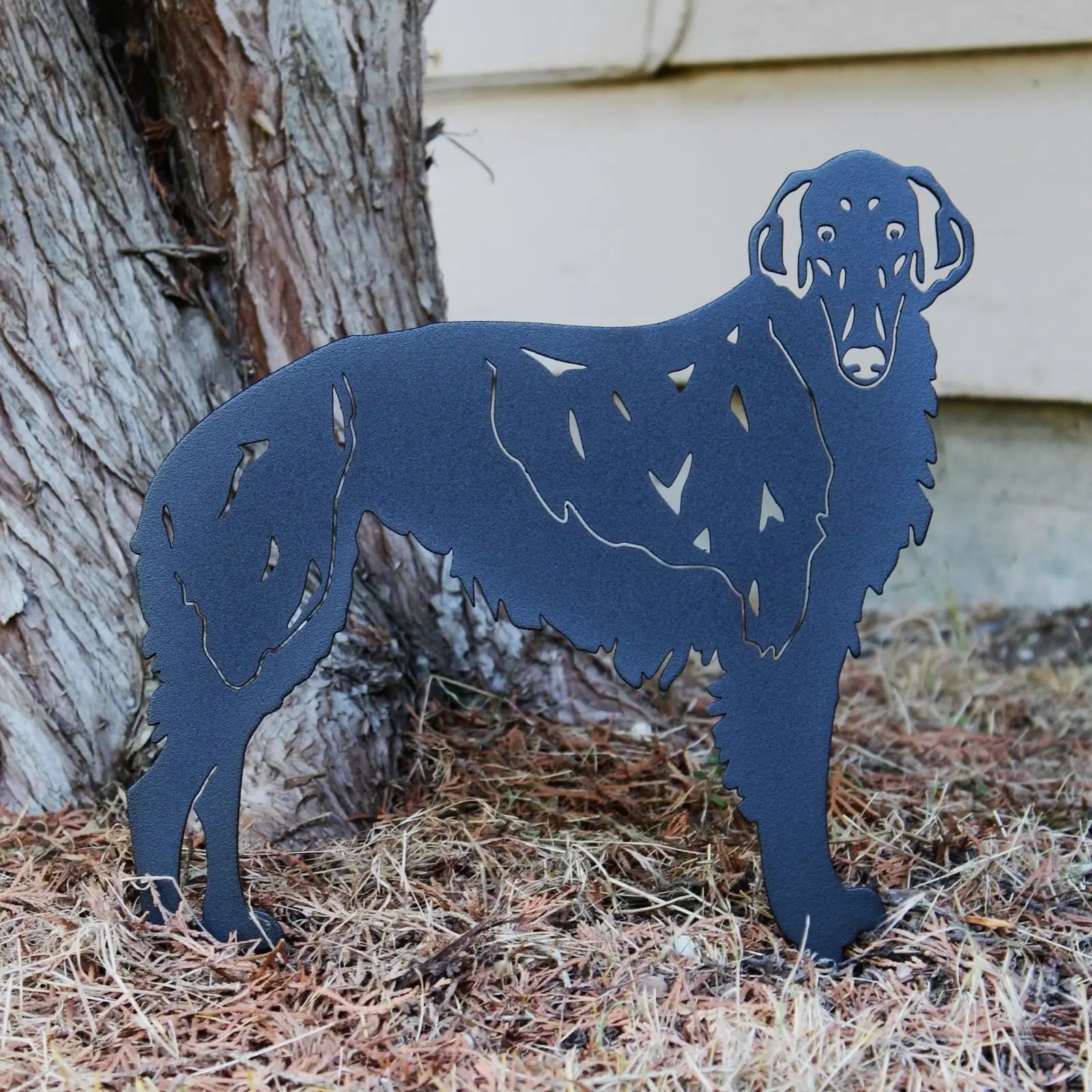 Silken Windhound metal silhouette in matte black, showcasing intricate cutouts, leaning against a tree.
