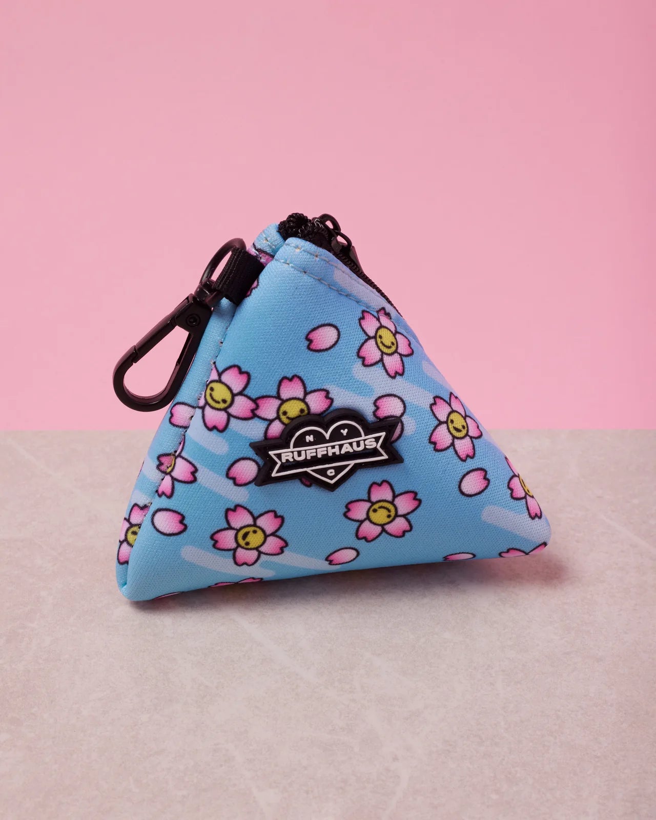 Compact blue dog poop bag holder with a floral design and smiling faces, featuring a swivel snap clasp for easy attachment.