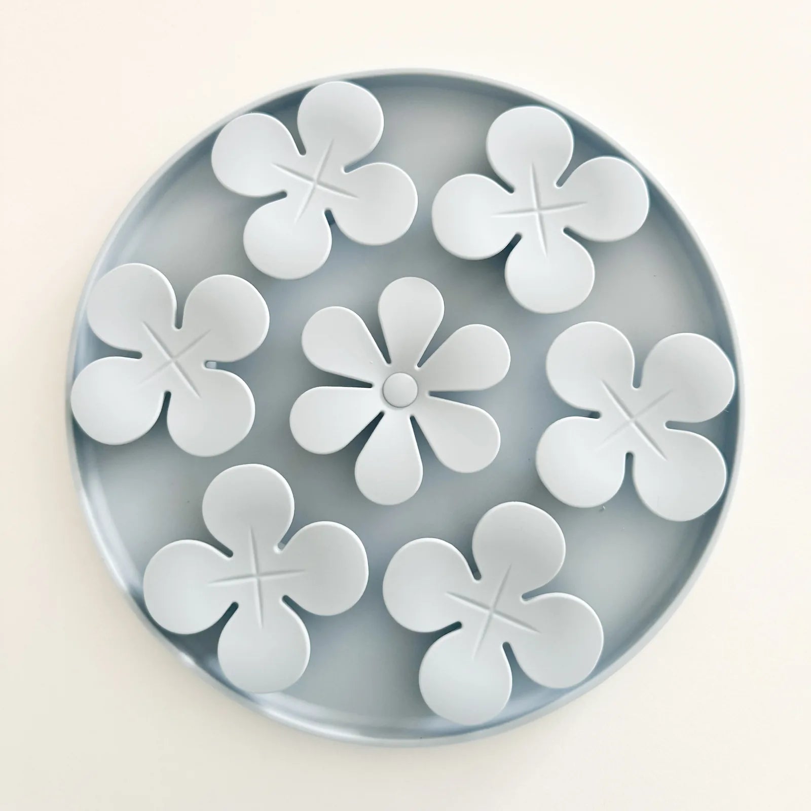 Light blue circular snuffle mat with flower-shaped designs, ideal for hiding treats and promoting foraging behavior in dogs.