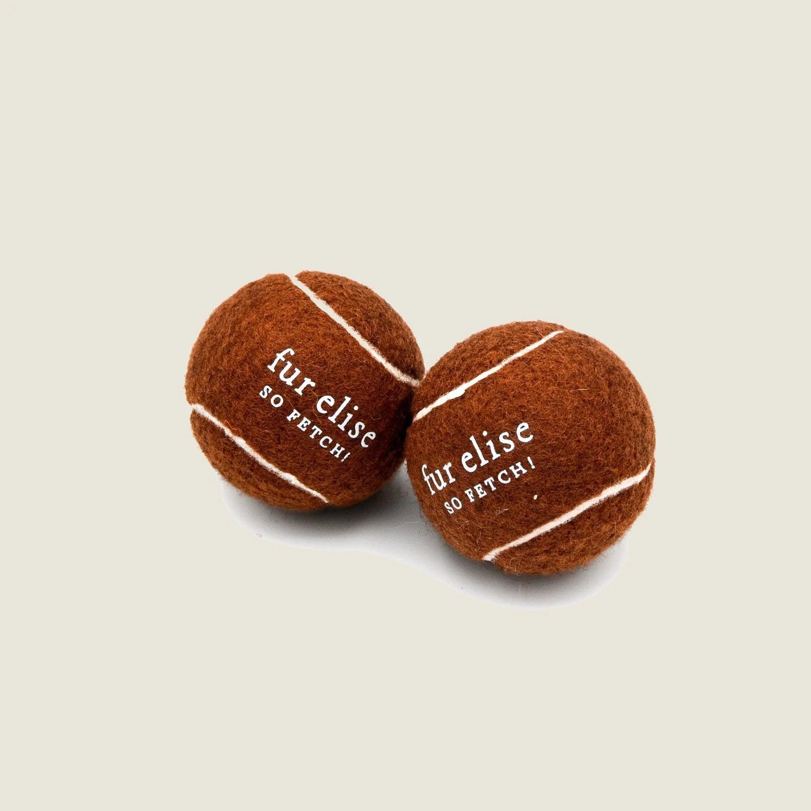 Brune tennis balls for dogs, featuring durable felt and natural rubber, with white stripes and branding.