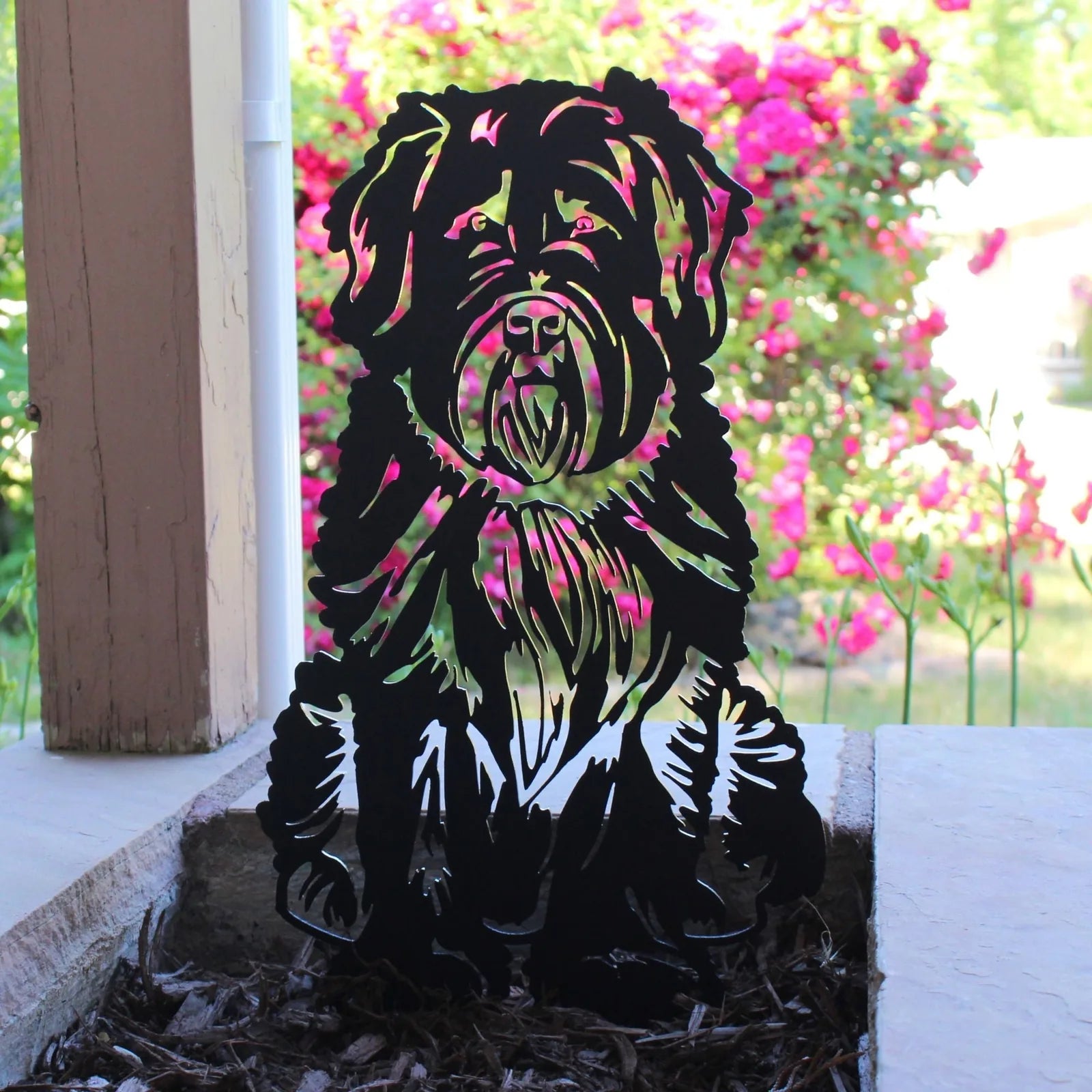 Black metal silhouette of a Soft Coated Wheaten Terrier set against vibrant green and pink floral background.