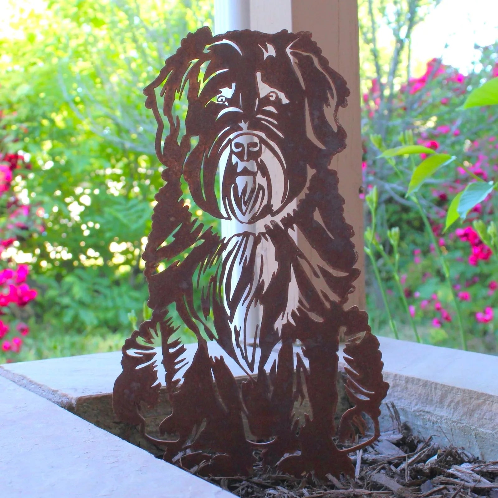 Soft Coated Wheaten Terrier metal silhouette in Corten steel, featuring intricate detailing against a colorful garden back...