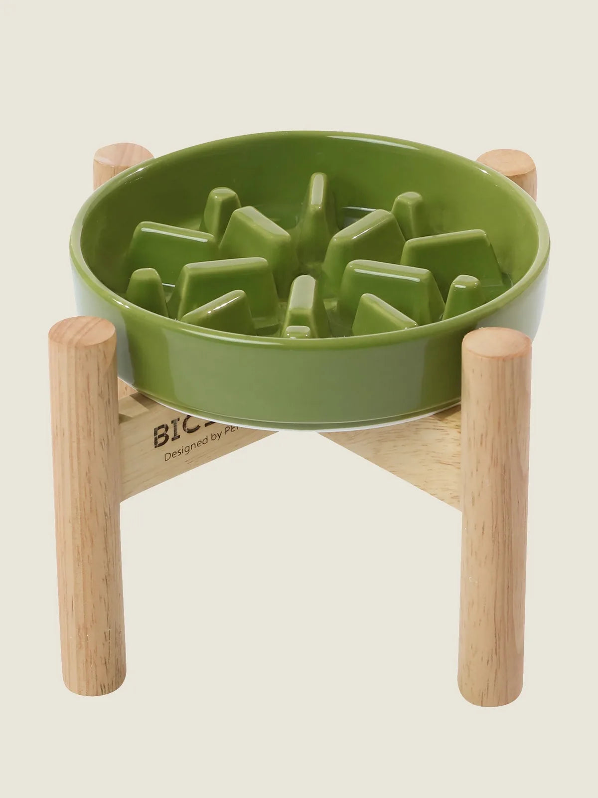 Green ceramic slow feeder dog bowl with ridges, placed on a light wood stand, promoting healthy eating habits.