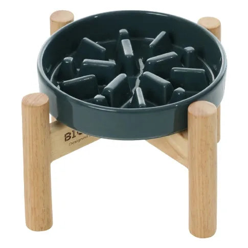 Ceramic slow feeder dog bowl in green, elevated on a wooden stand, designed to promote slower eating and better digestion.