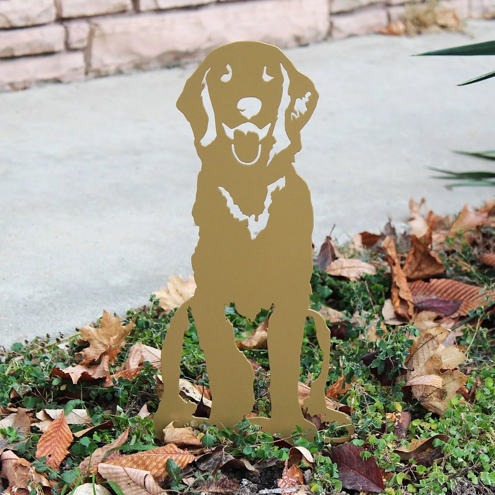 Gold metal silhouette of a sitting Golden Retriever surrounded by fallen leaves, ideal for outdoor decor.