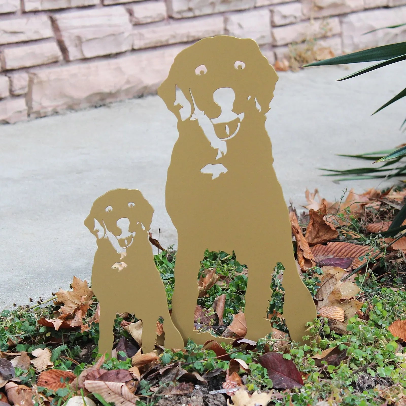 Handmade gold metal silhouette of a Labrador Retriever and puppy, set against a natural outdoor backdrop.