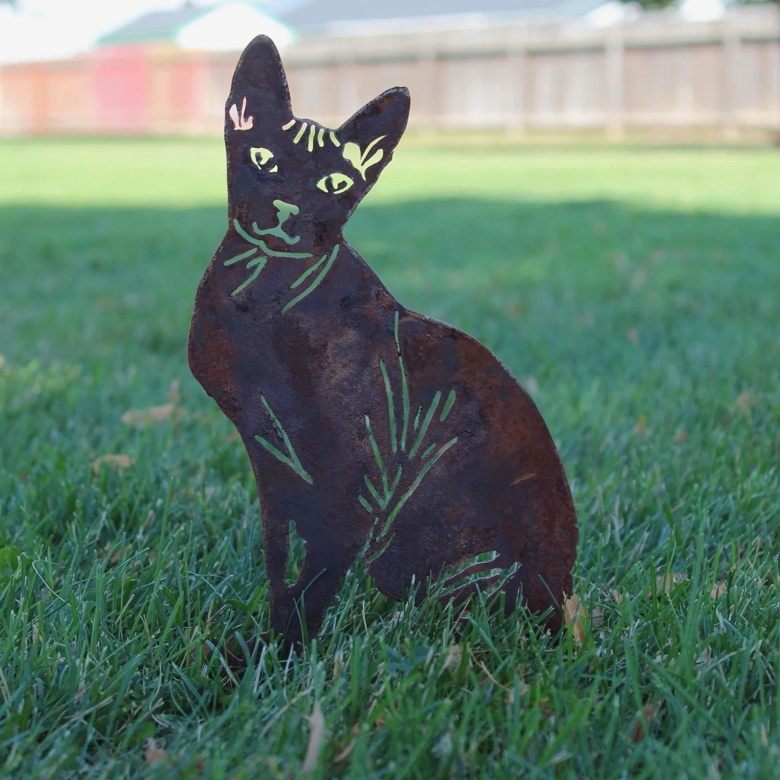 Sphynx cat silhouette made of rusted Corten steel, displayed in a grassy yard with natural detailing.