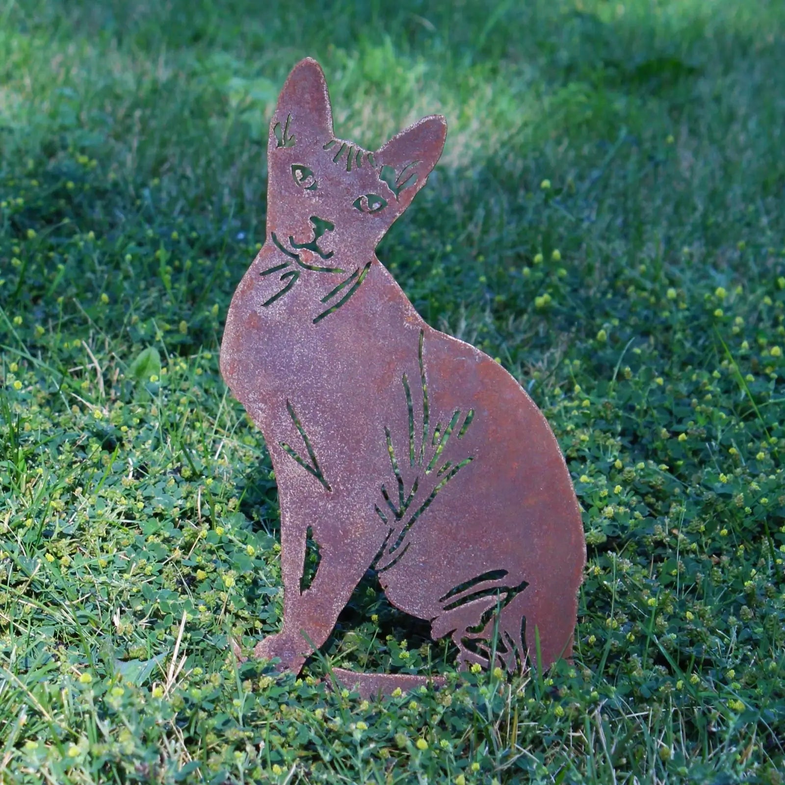 Rusty Corten steel Sphynx silhouette garden art, elegantly designed, seated on green grass.