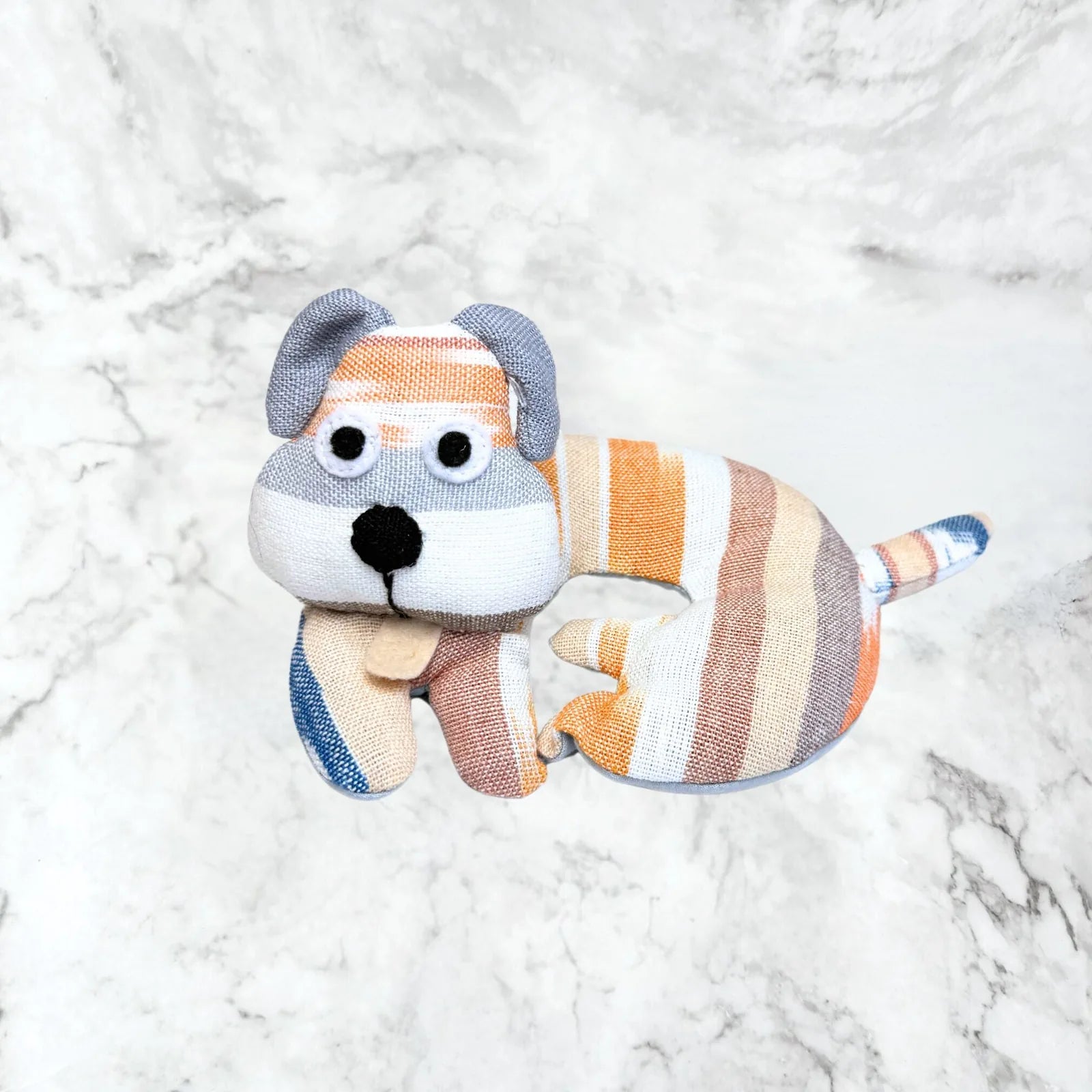 Striped fabric dog trivet in orange, gray, and cream, featuring a playful design and cute facial details.