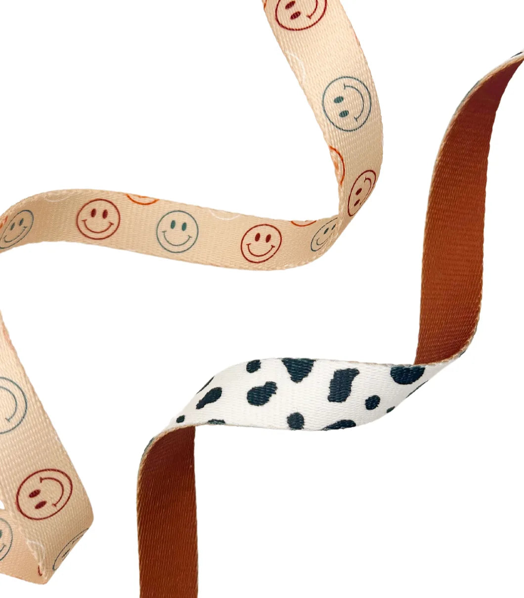 Spotted Ember Leash featuring a playful smiley face pattern on a peach background and a black-spotted design on white.