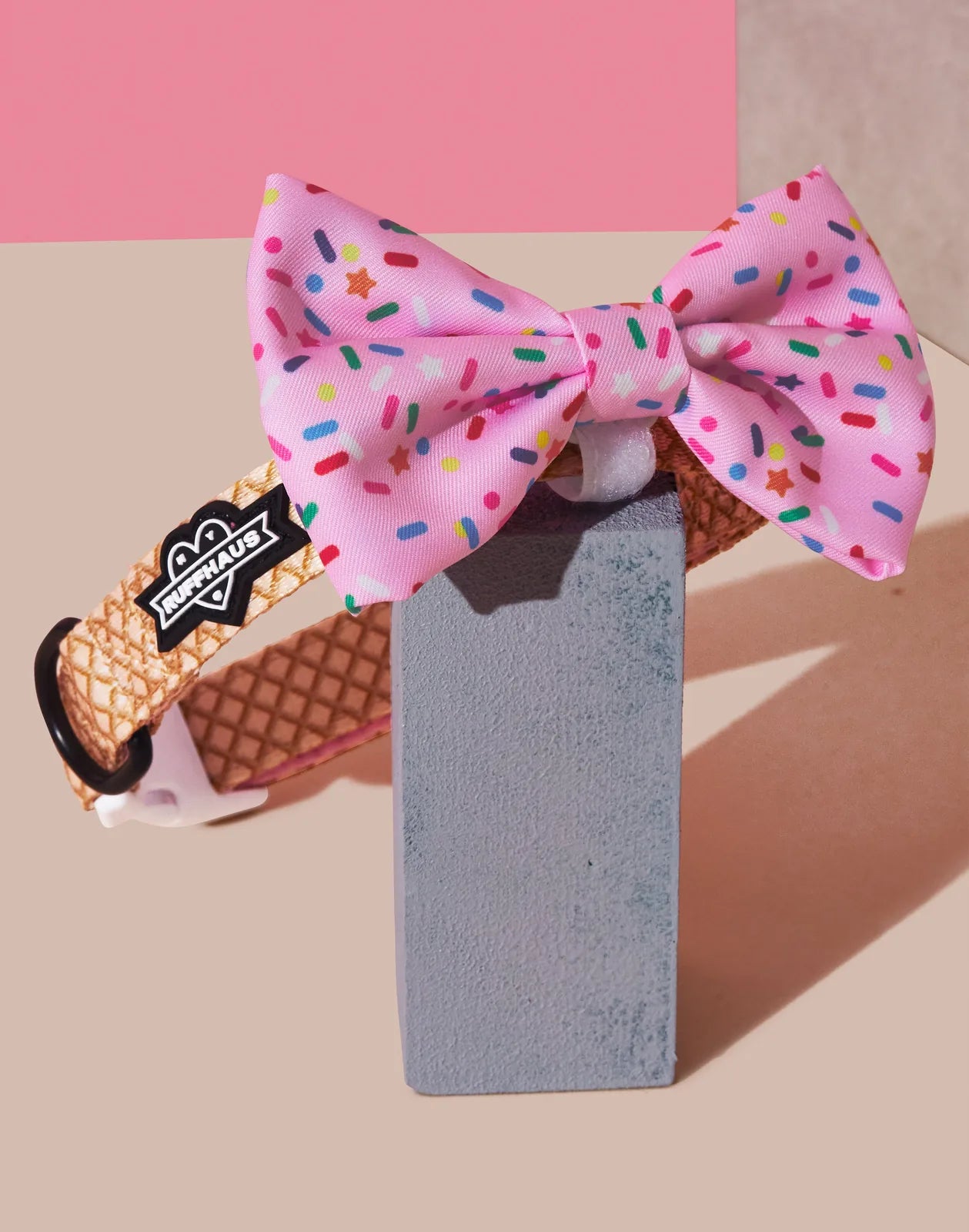 Pink dog collar with a sprinkles-patterned bowtie, featuring a durable webbing design and RUFFHAUS NYC logo.