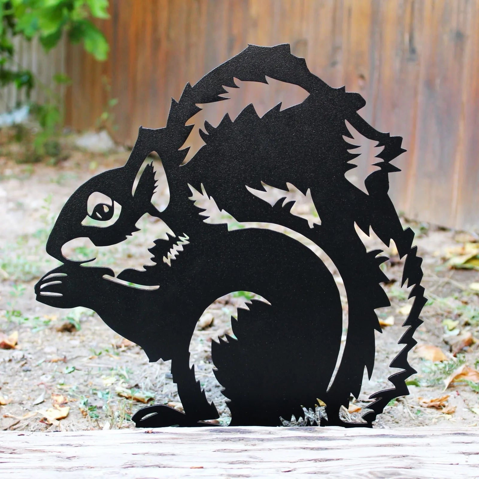 Black metal silhouette of a squirrel, showcasing intricate details and leaf patterns, perfect for outdoor garden decor.