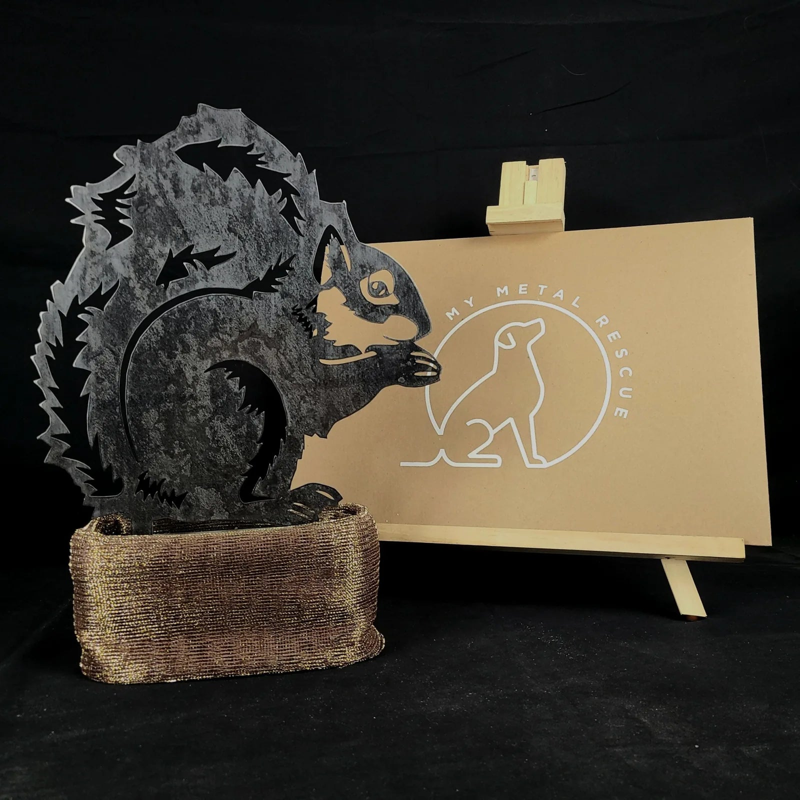 Handcrafted black metal squirrel silhouette on a textured bronze base, showcasing outdoor garden decor elegance.
